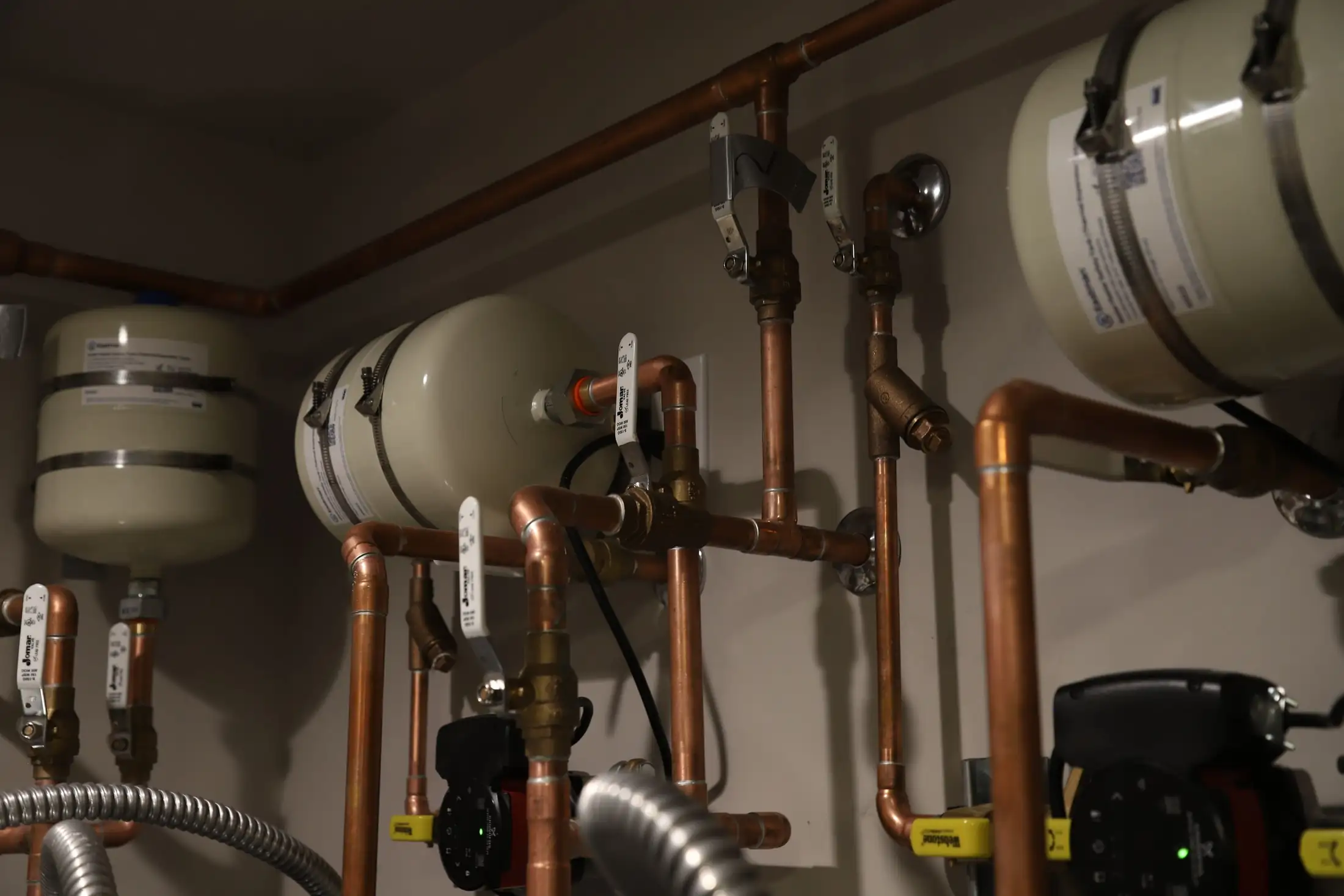 Copper water lines, ball valves and expansion tanks on a mechanical room wall at Thrive Center in Hailey