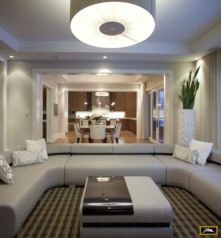 Image of Modern living room with sectional sofa, coffee table, and kitchen in background, KHD Homes design-build interior.
