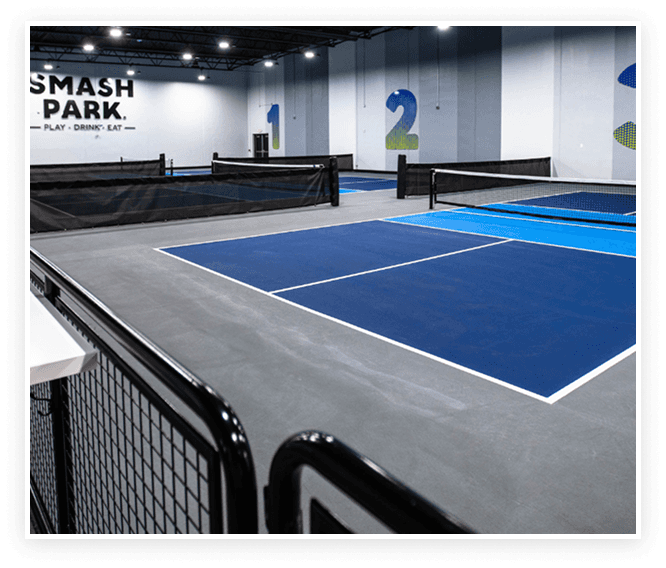 Blue indoor pickleball courts at Smash Park with netted court dividers