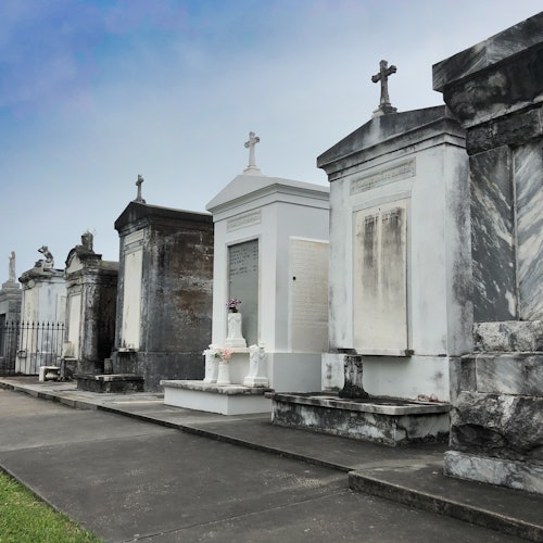 一排地上墓穴排列在墓地中，顶部有十字架的陵墓，笼罩在阴云密布的天空下。