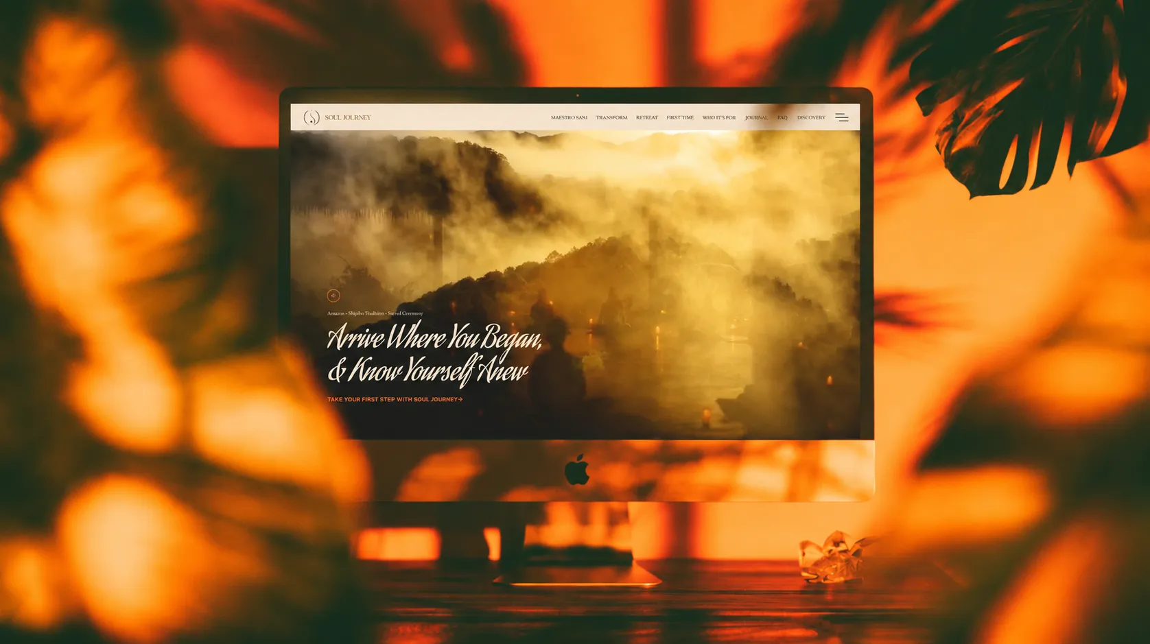 iMac displaying the Soul Journey website surrounded by warm botanical shadows