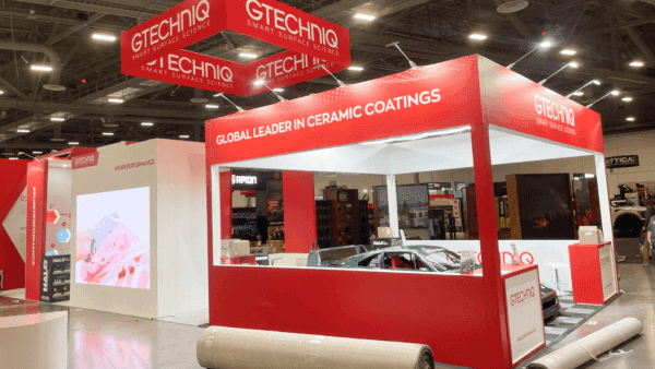 Detailed view of a large SEMA booth showing vehicle-focused layout, branded display hierarchy, and open show-floor access