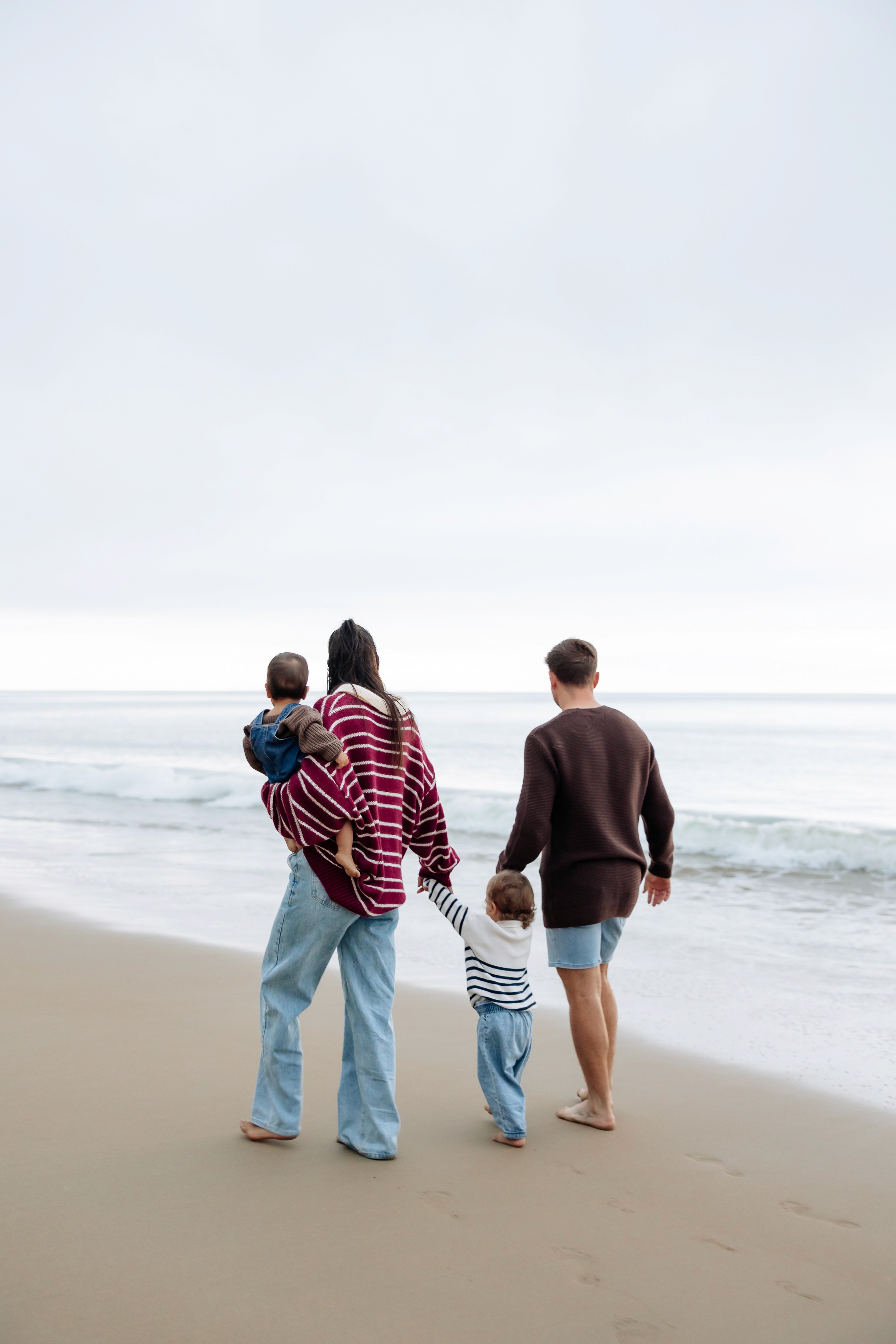 Family walking together along the beach during a winter photography session in Mackay with soft sunset light