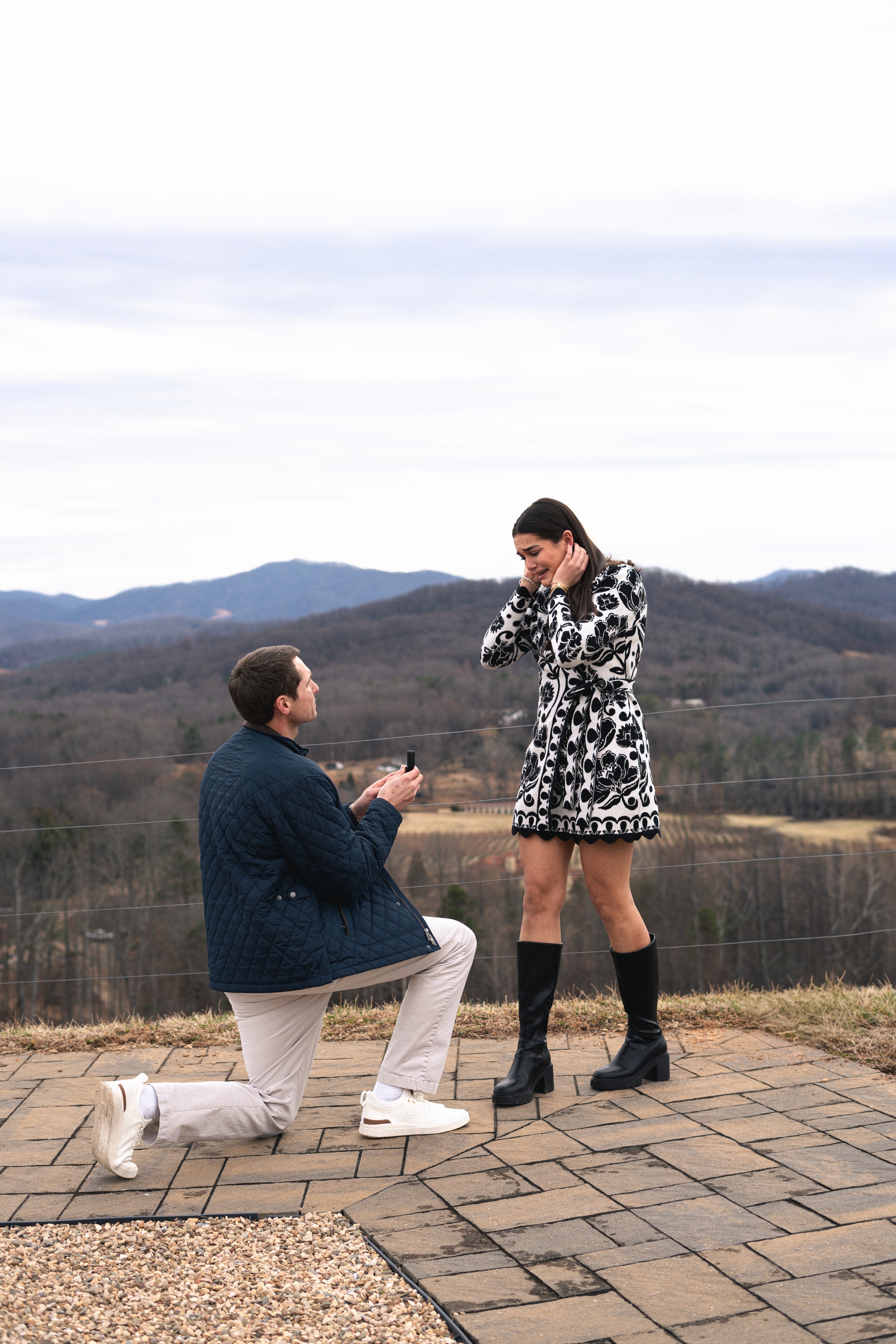 A groom in a gray suit carries his bride.