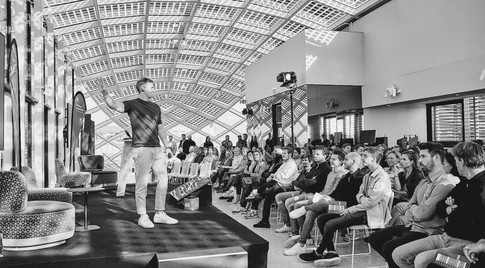 Flatline Agency founder speaking on stage to a full audience under a glass roof