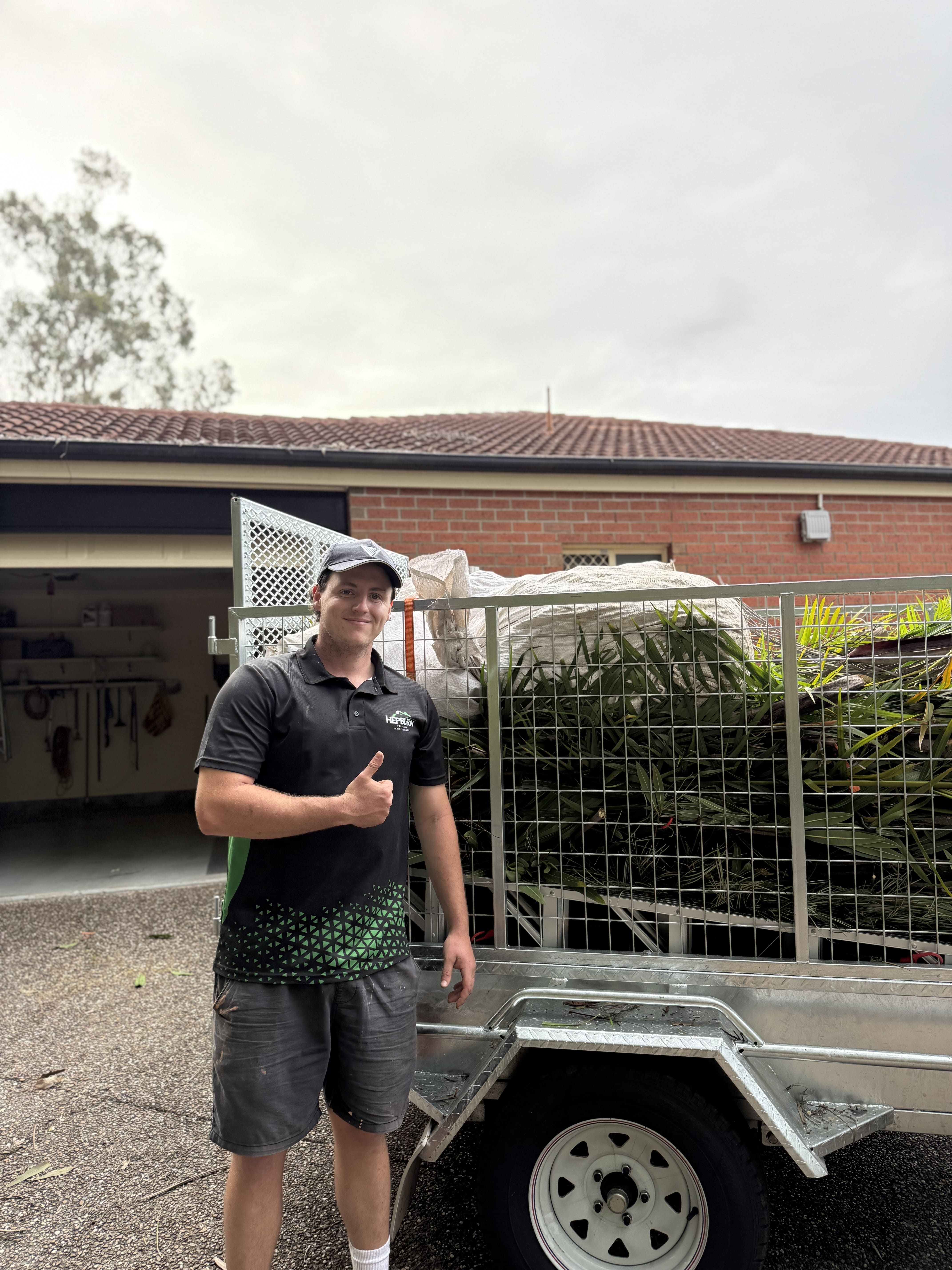 Hepburn Property Maintenance team member with green waste removal trailer after garden clean up Gold Coast