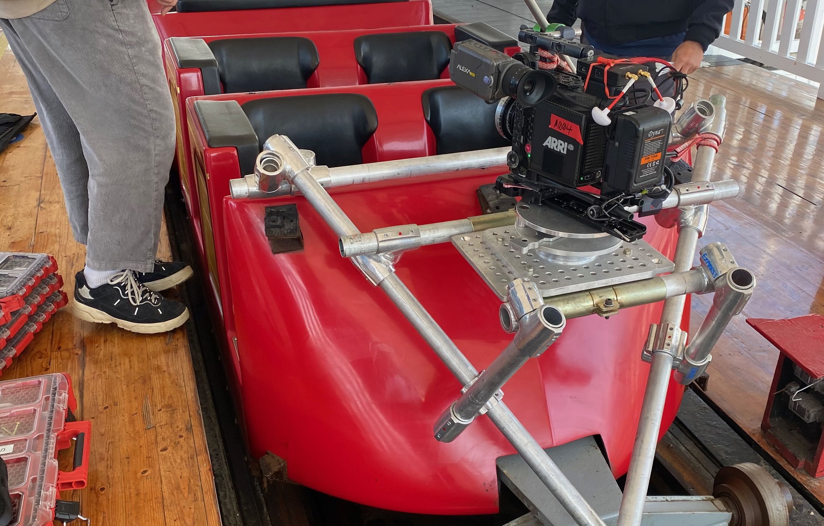 ARRI camera mounted on a speedrail rig extending from the front of a roller coaster car at Belmont Park, San Diego, with crew member inspecting the setup