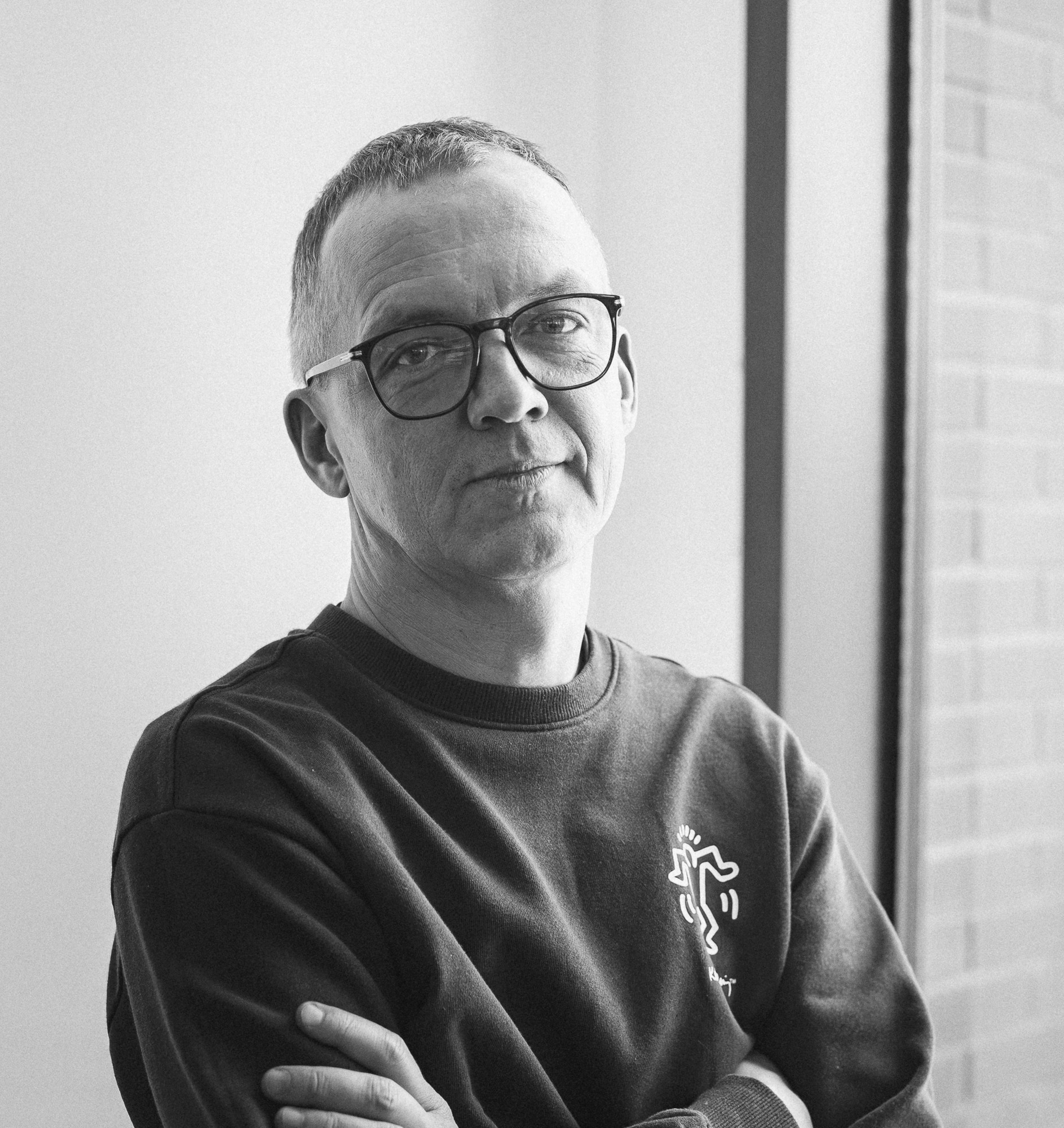 A thoughtful young person with dark hair gazes to the side, captured in soft black and white lighting.