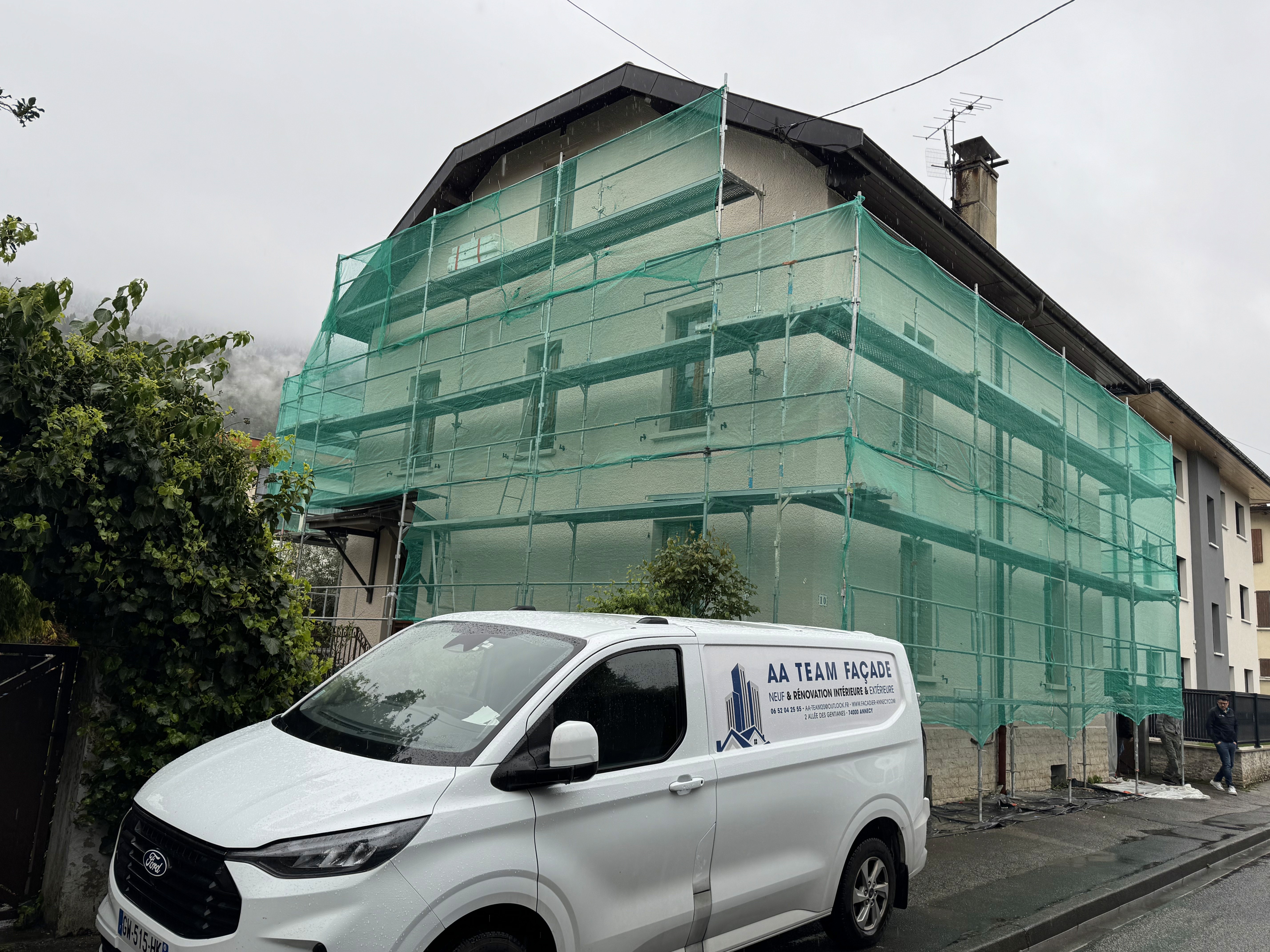Maison avec échafaudage vert pendant un ravalement de façade