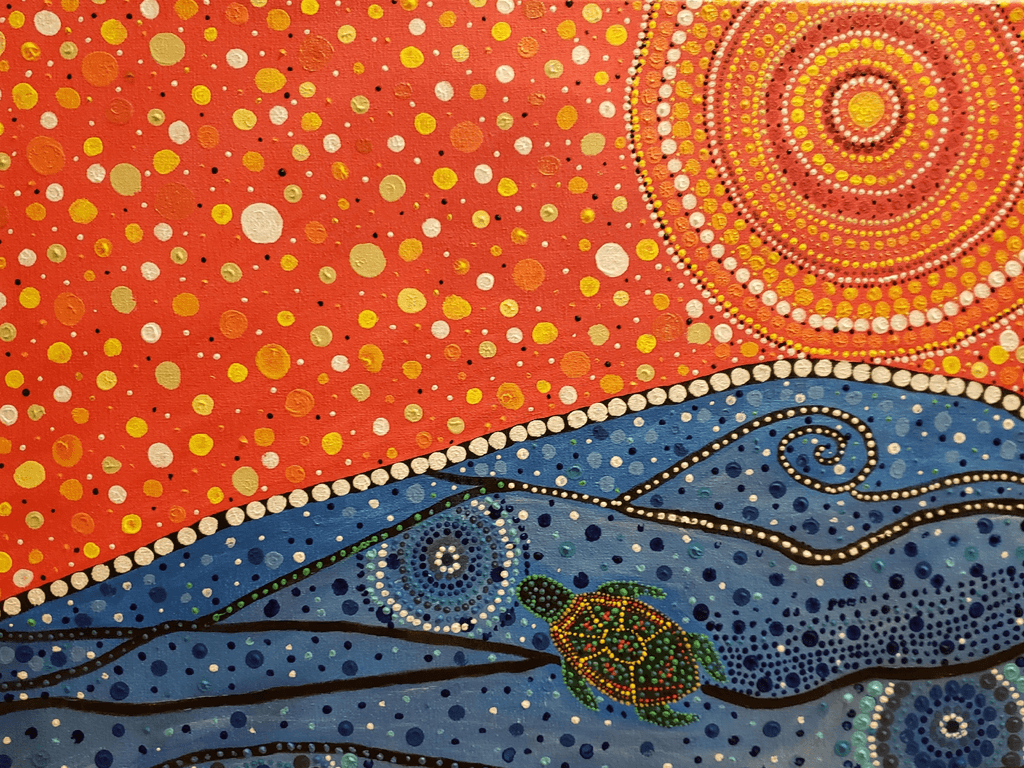 Pointillism painting by a Cree artist featuring a turtle in the water and a brilliant orange sun above.