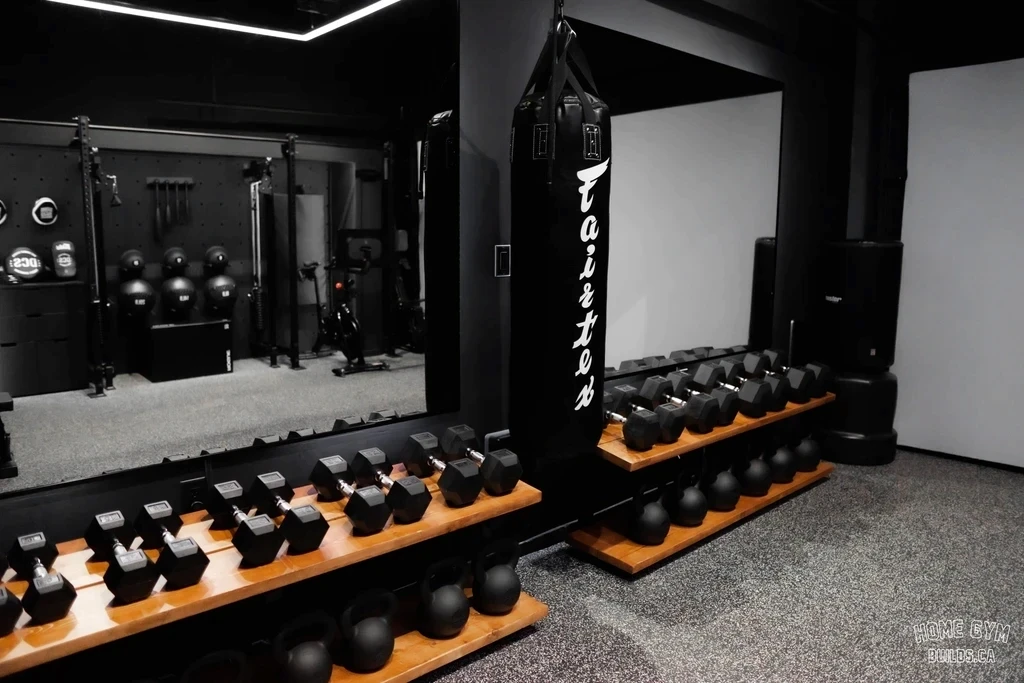 Luxury custom home gym featuring dumbbell and kettlebell storage, mirrored walls, and a heavy boxing bag, designed by Home Gym Builds in Canada.