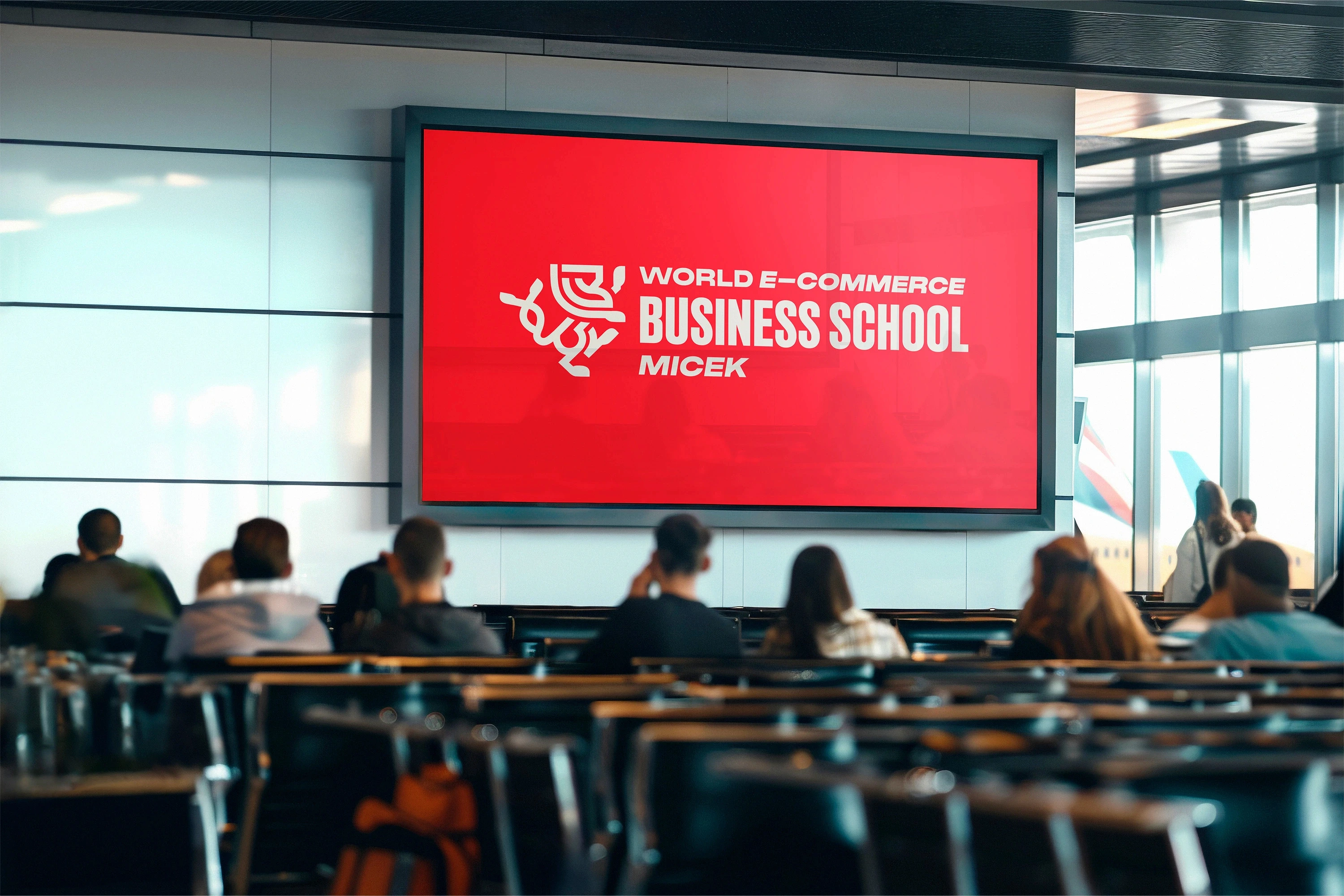 Prezentace loga World E-commerce Business School Míček na velké obrazovce v moderní učebně, před kterou sedí studenti