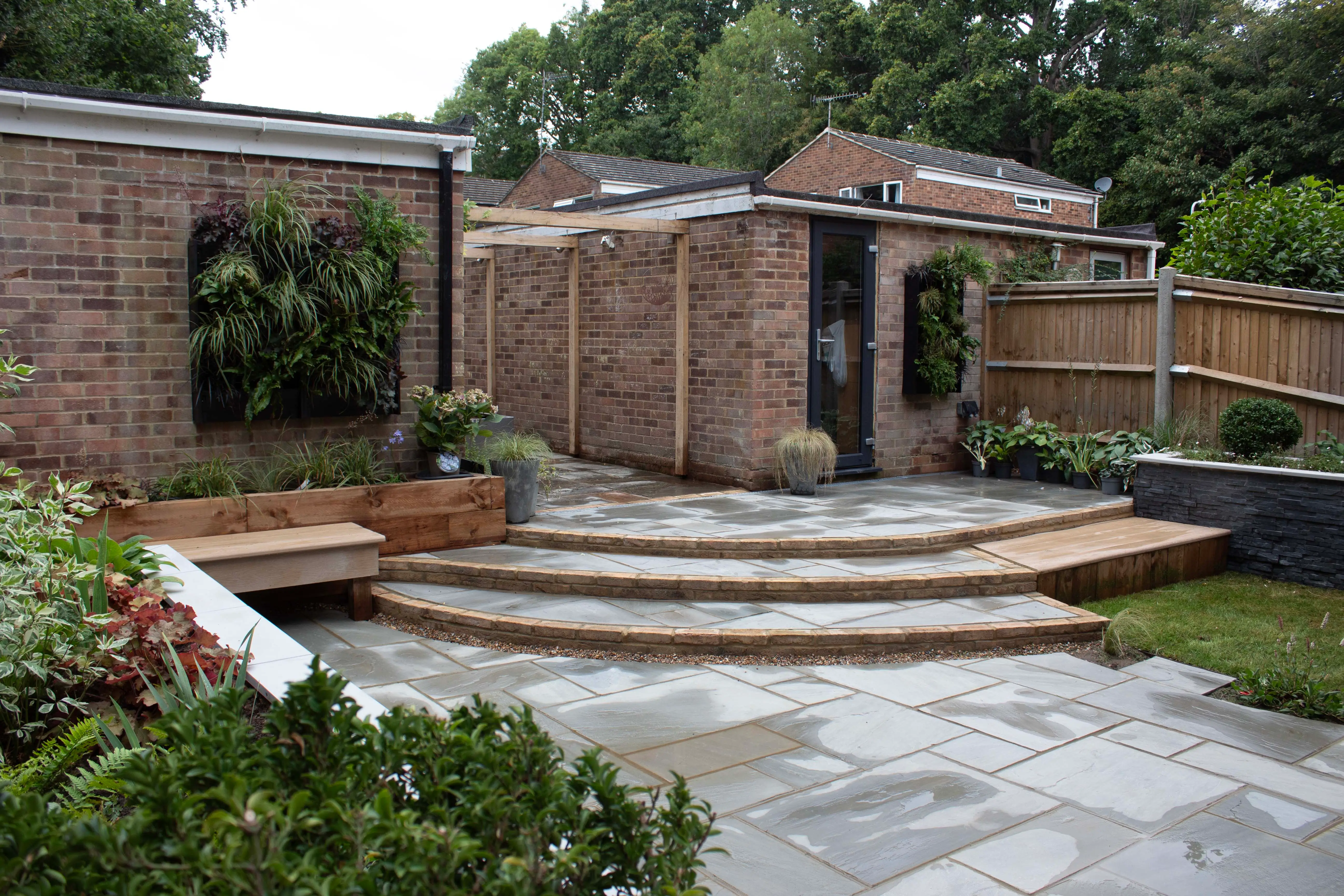A landscaped outdoor area featuring stone steps, brick walls, and green foliage, creating a serene environment.