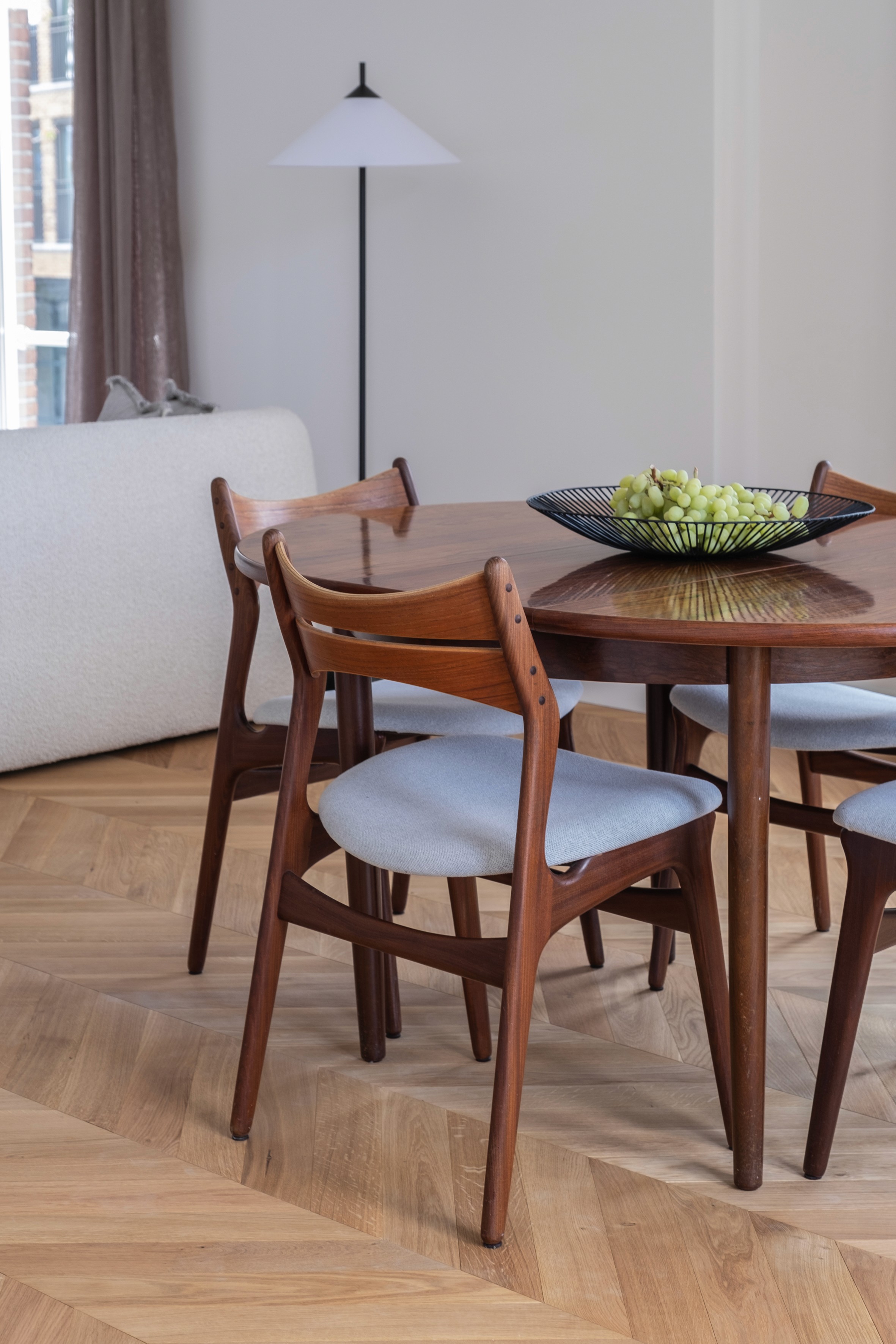 Mid-century rosewood dining table and chairs on herringbone parquet floor with wire fruit bowl