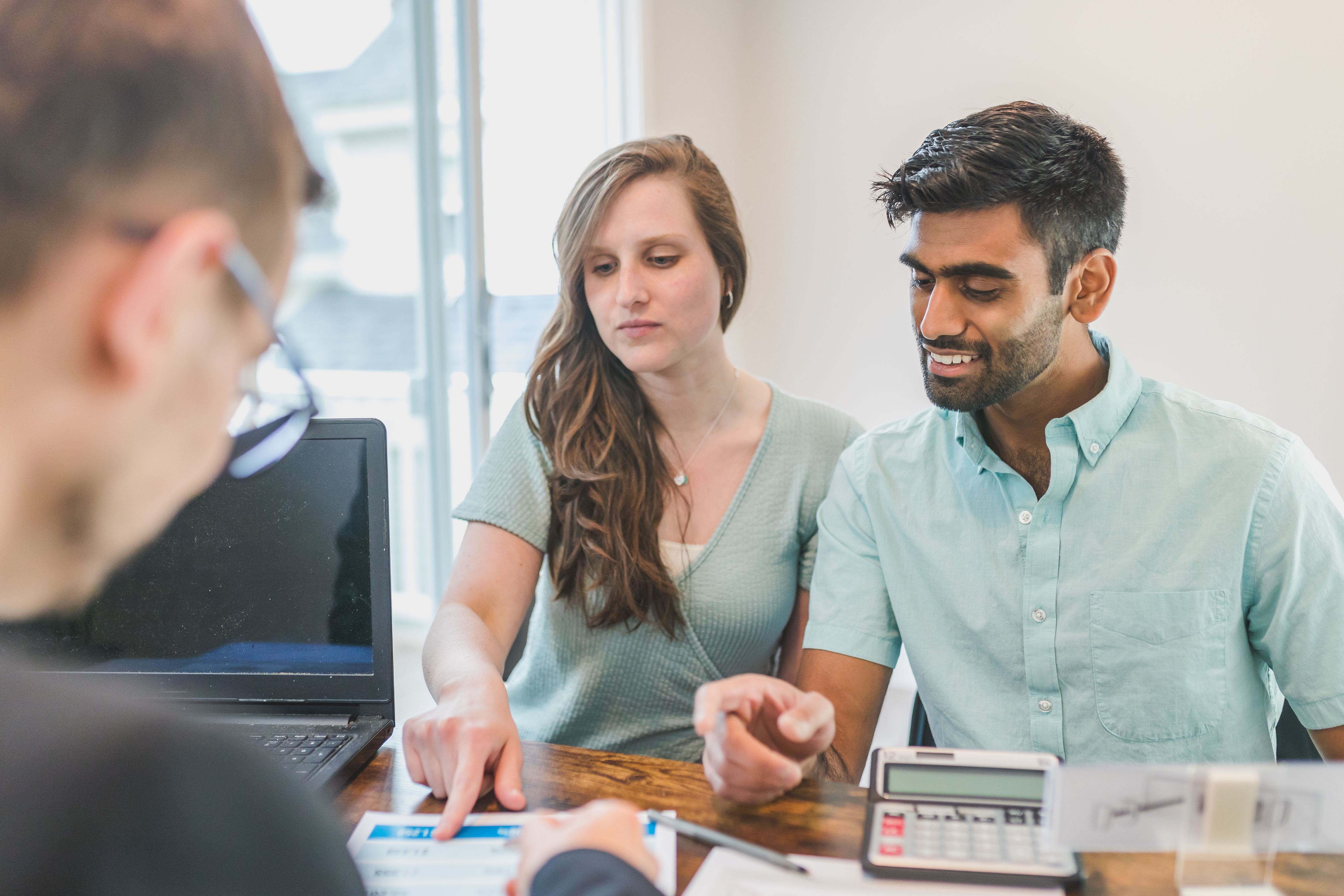 young-couple-consulting-with-a-financial-advisor-using-a-calculator-and-document