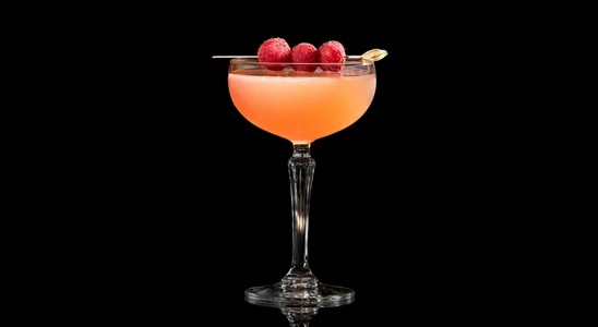 A closeup of a French Martini drink against a dark background.