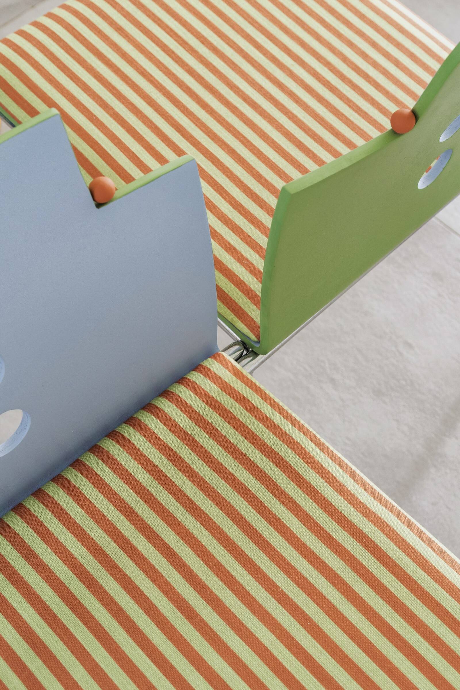 Close-up of colorful living room furniture with striped orange and green patterns, high contrast modern design.