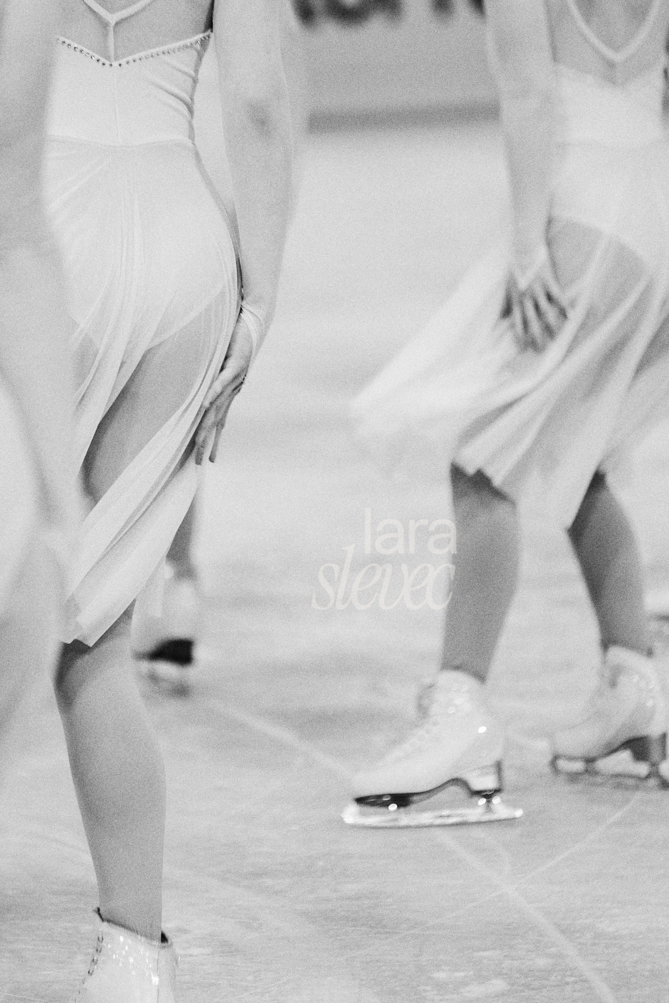 Emotionales und Sanftes Schwarz Weiß Bild von Eiskunstläuferinnen im Synchroneiskunstlauf. Detailaufnahme des Kostüms mit der Hand am Oberschenkel. Team Colibris Vienna. ISU Synchronized Skating Championships 2026 in Salzburg. Fotografiert von Lara Slevec.