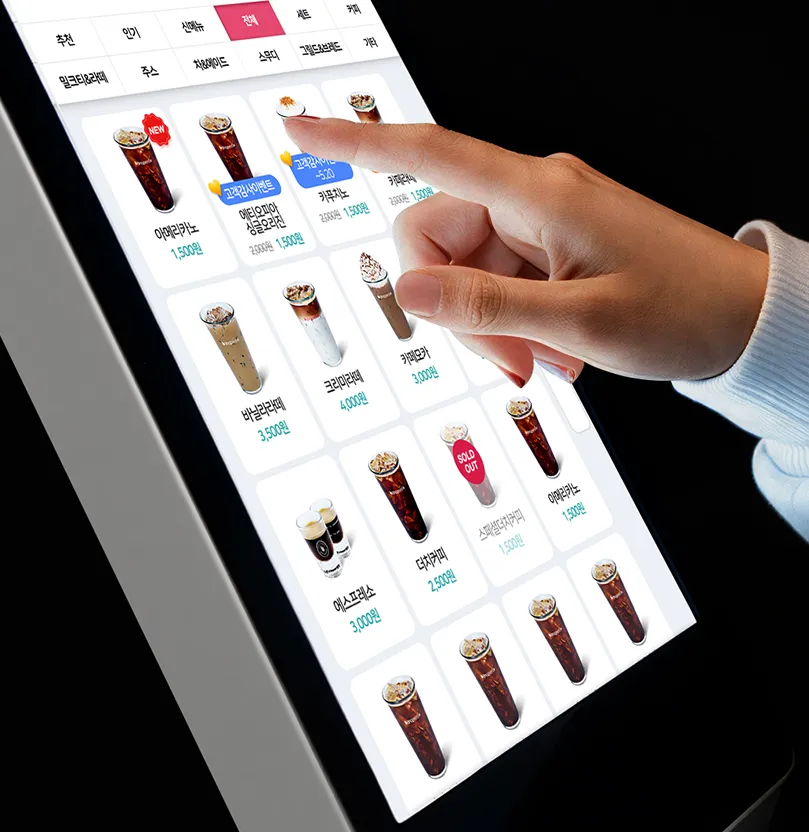 다양한 음료 메뉴가 배열된 키오스크 화면에서 항목을 터치해 선택하는 장면