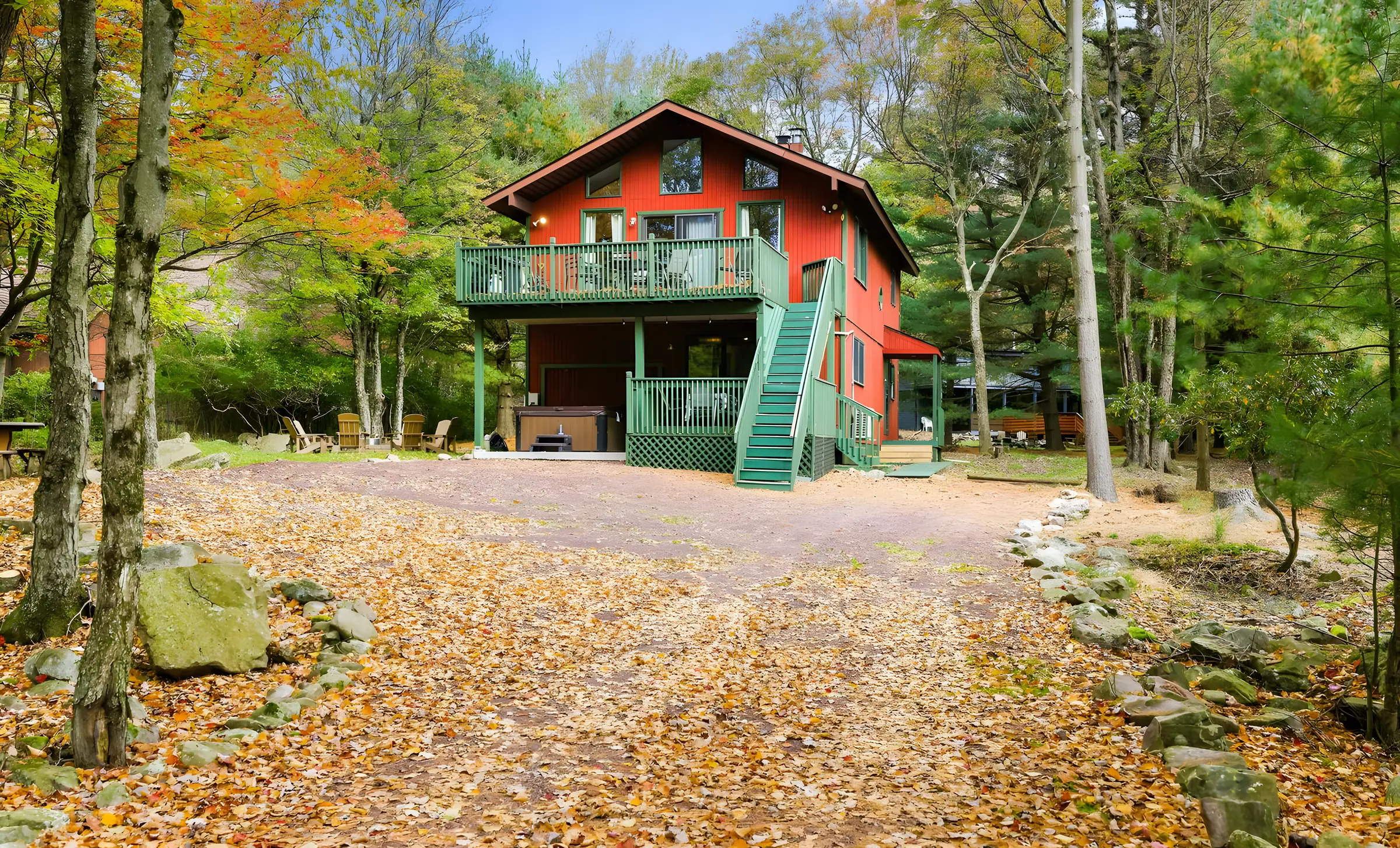 Red two-story chalet with green deck and stairs in fall woods, RedHawk Chalet, Lake Harmony, PA