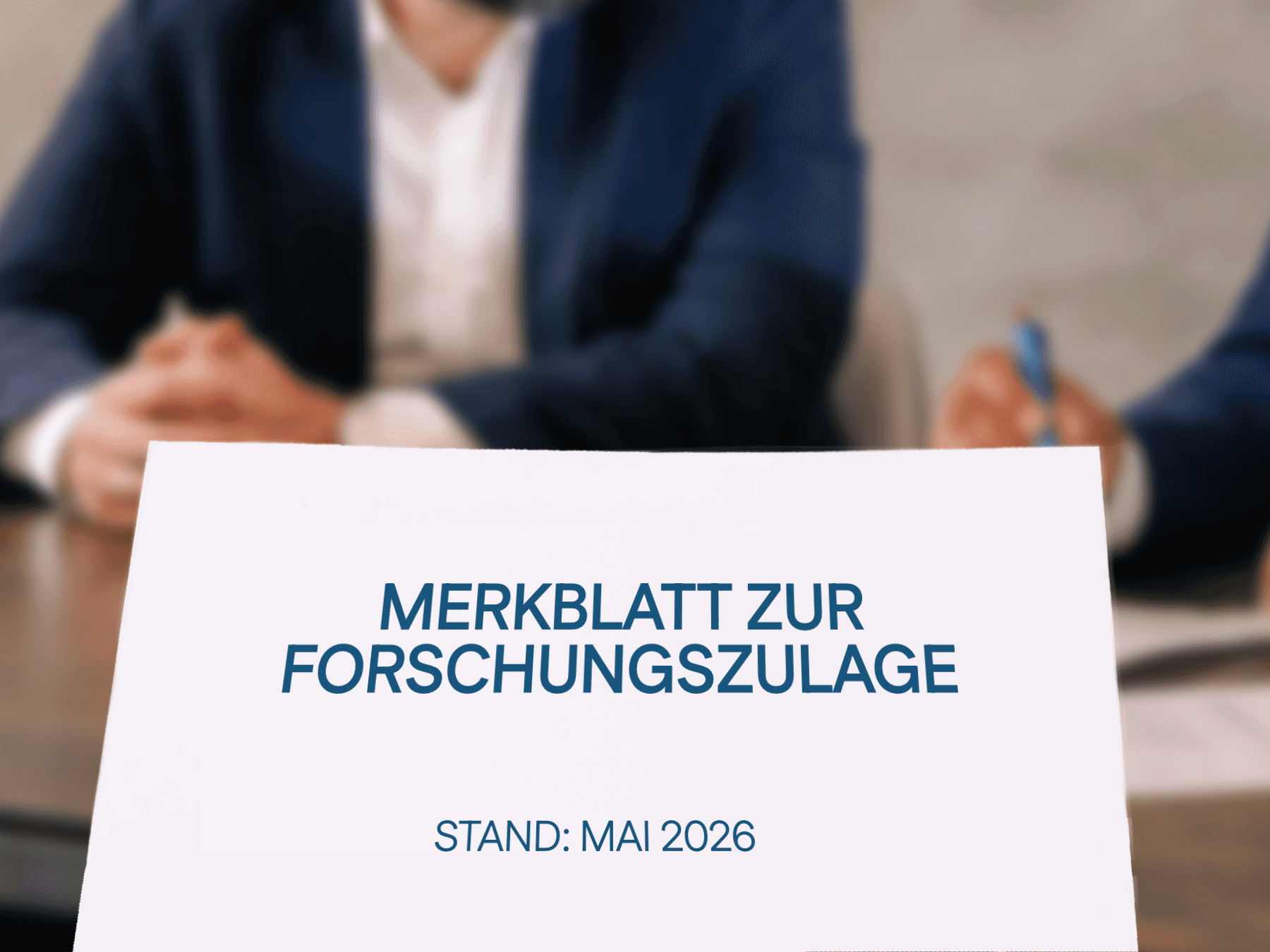 Geschäftliches Meeting: Personen im Anzug sitzen an einem Tisch mit Laptop und Unterlagen.