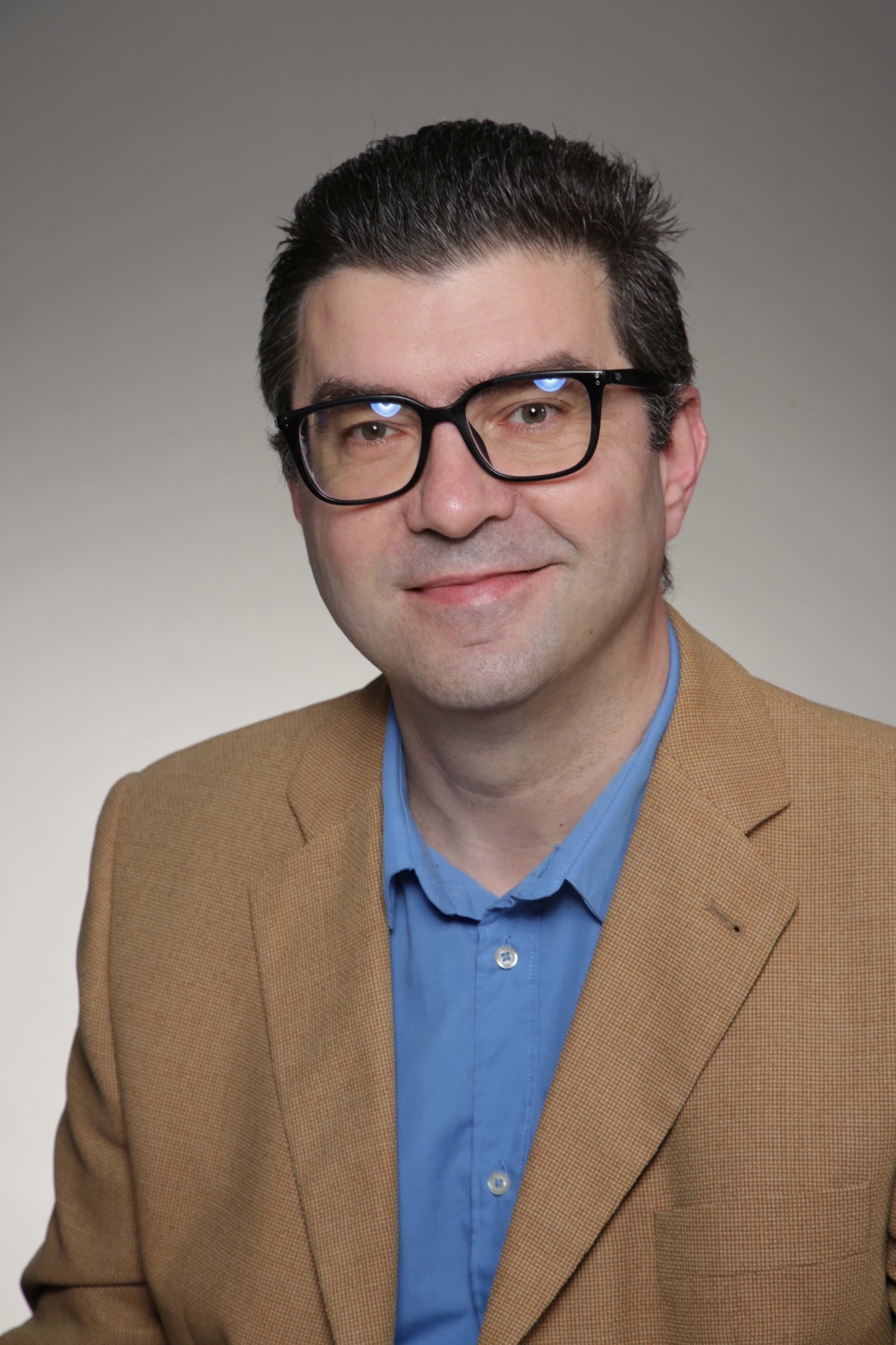 Two people looking at a laptop, one points at the screen. Man wears a cap and glasses. Woman in a green shirt.