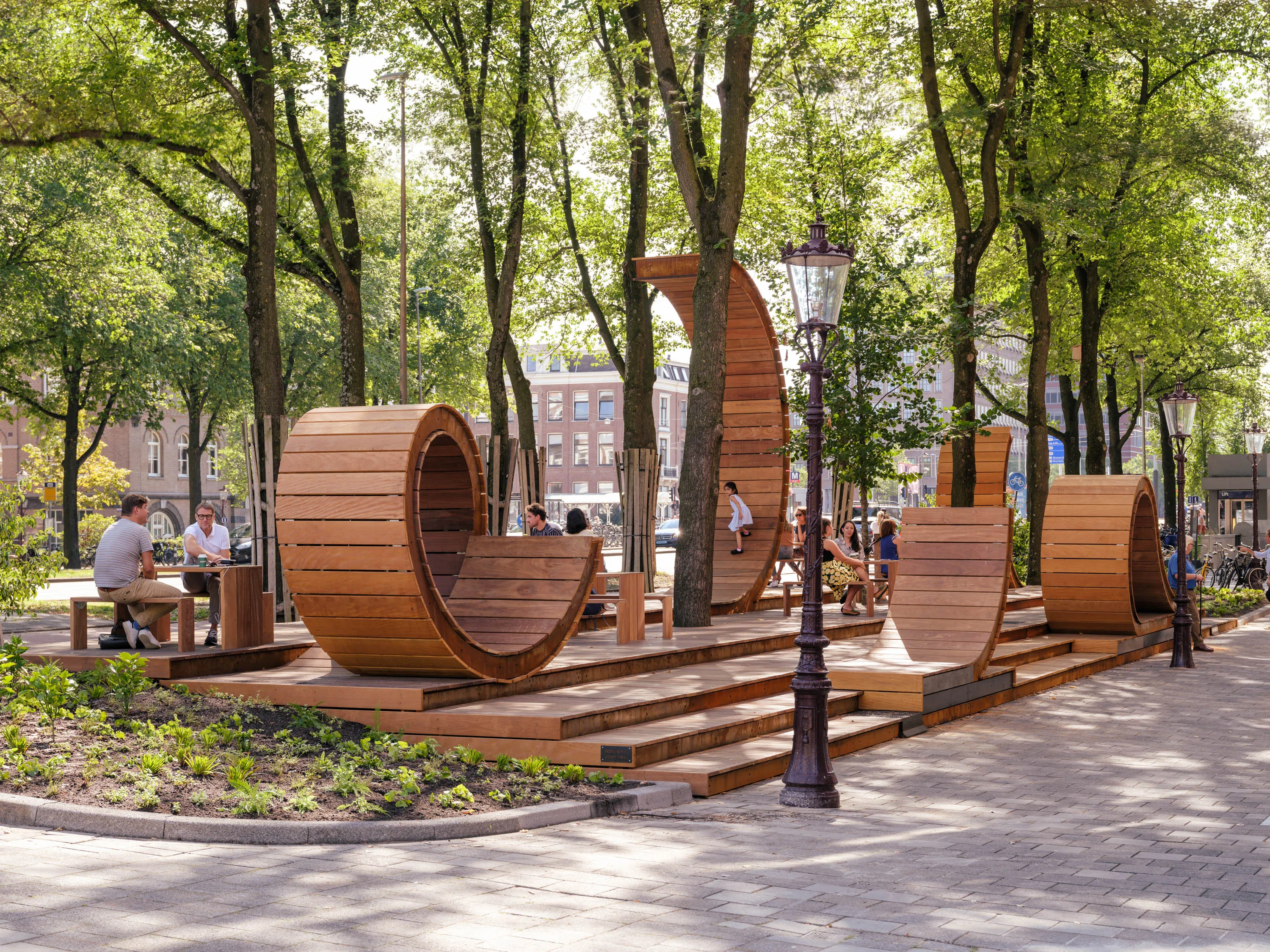 Wooden playground structure shaped like large wheels, surrounded by trees in a natural setting.