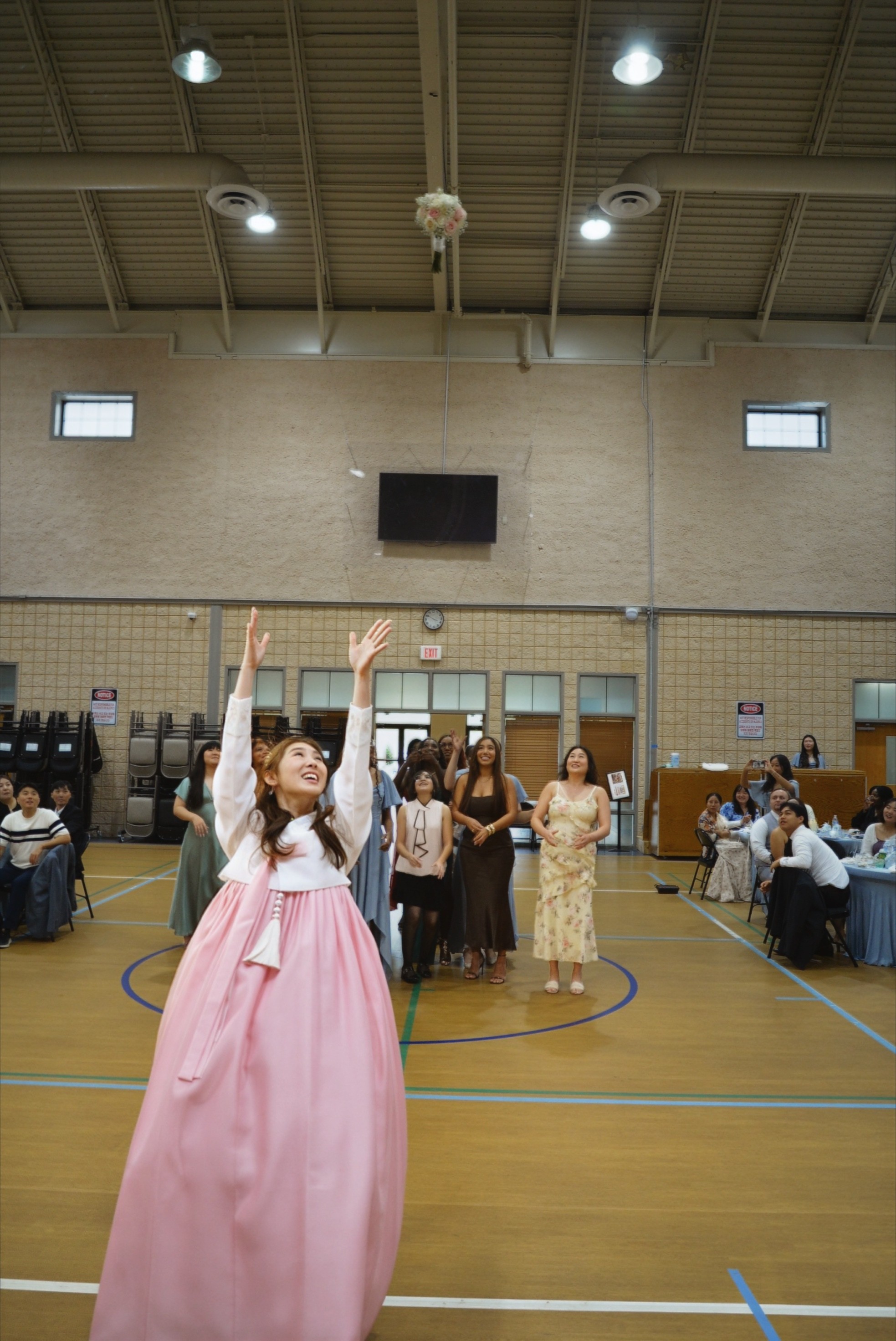 Bride in hanbok tossing her bouquet at the church gym reception — Korean wedding Duluth GA