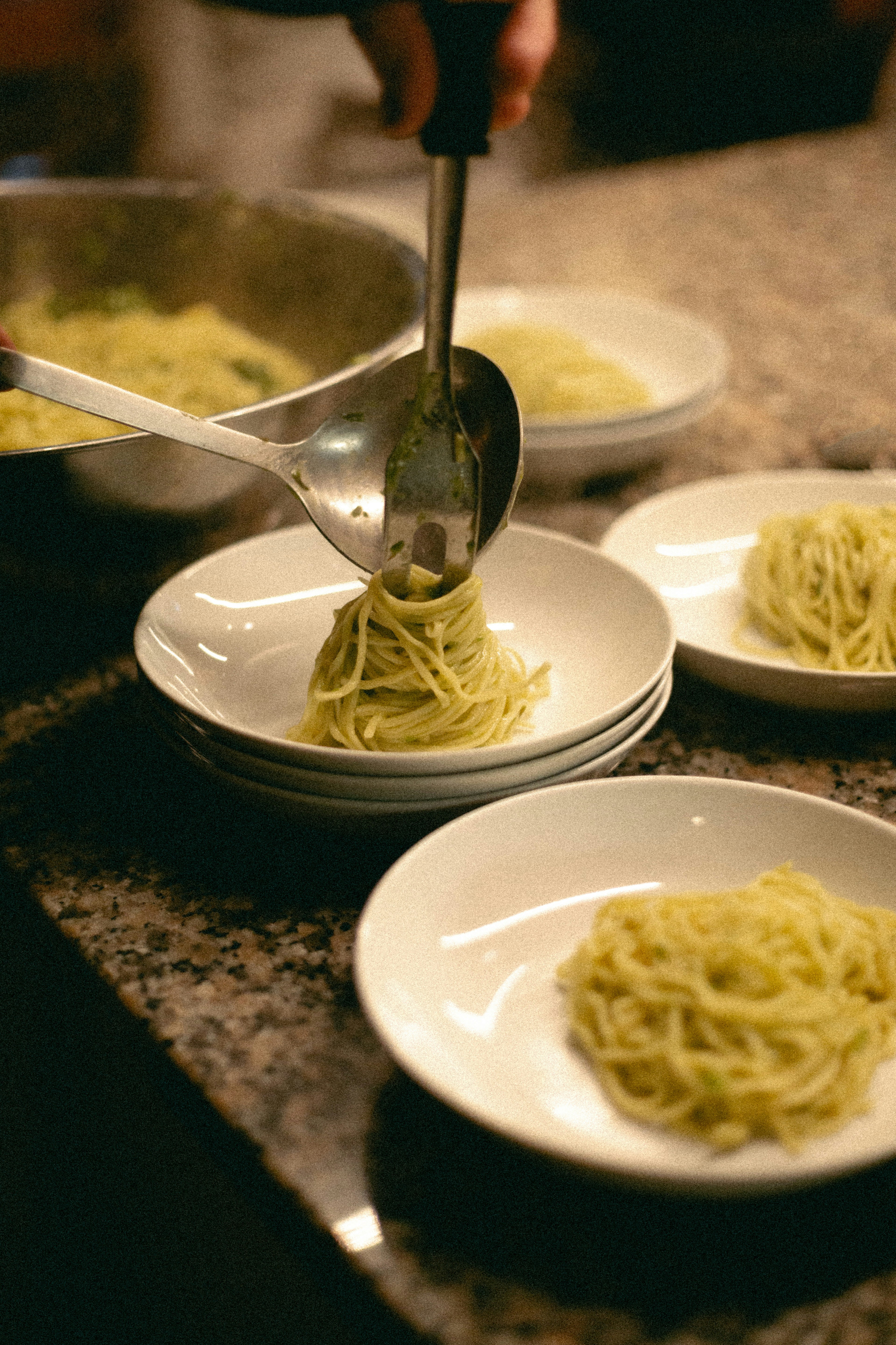 a person is spooning spaghetti into a bowl