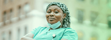 Smiling healthcare worker in scrubs outdoors.