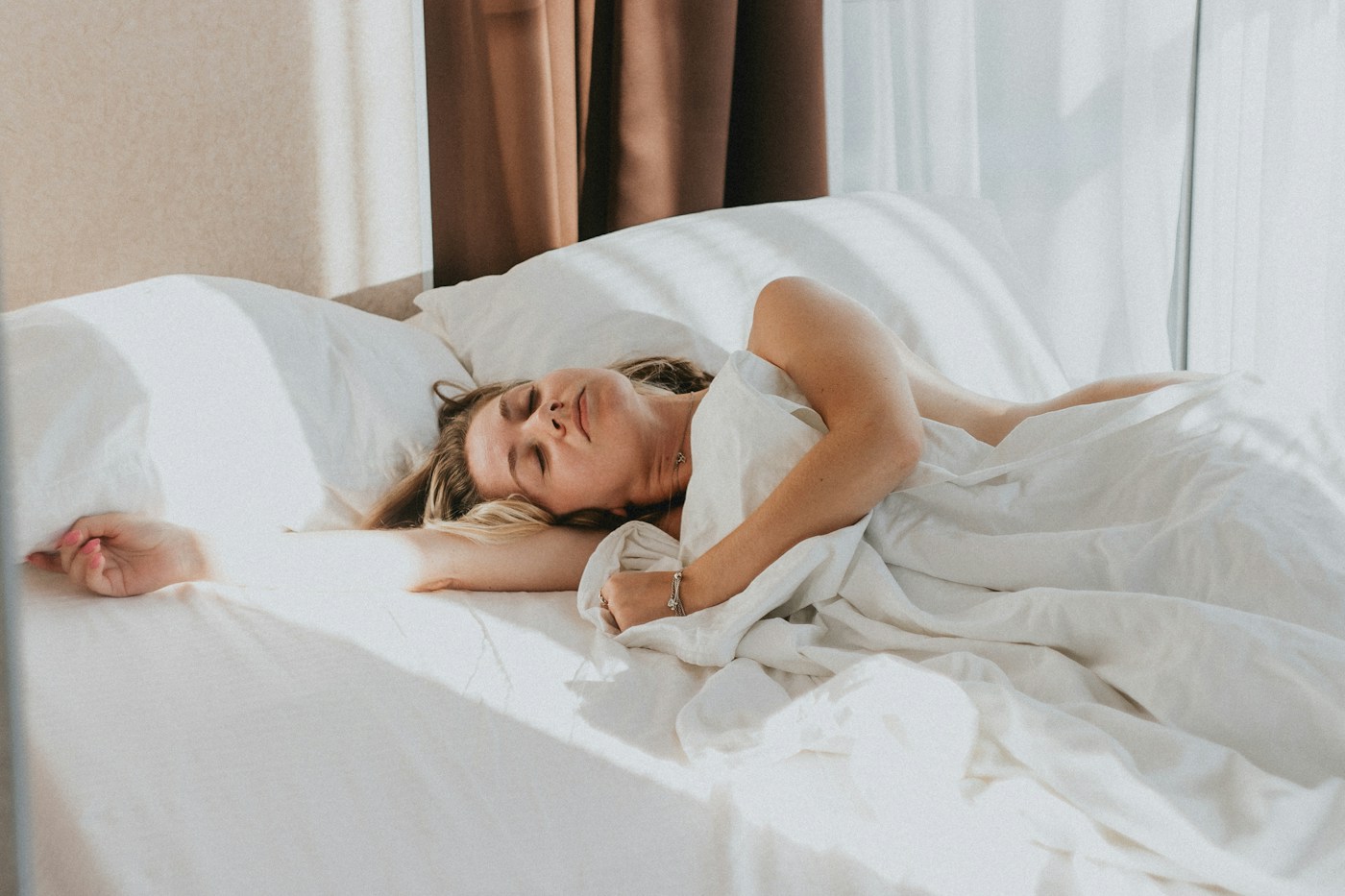 A woman resting peacefully in a naturally lit bedroom