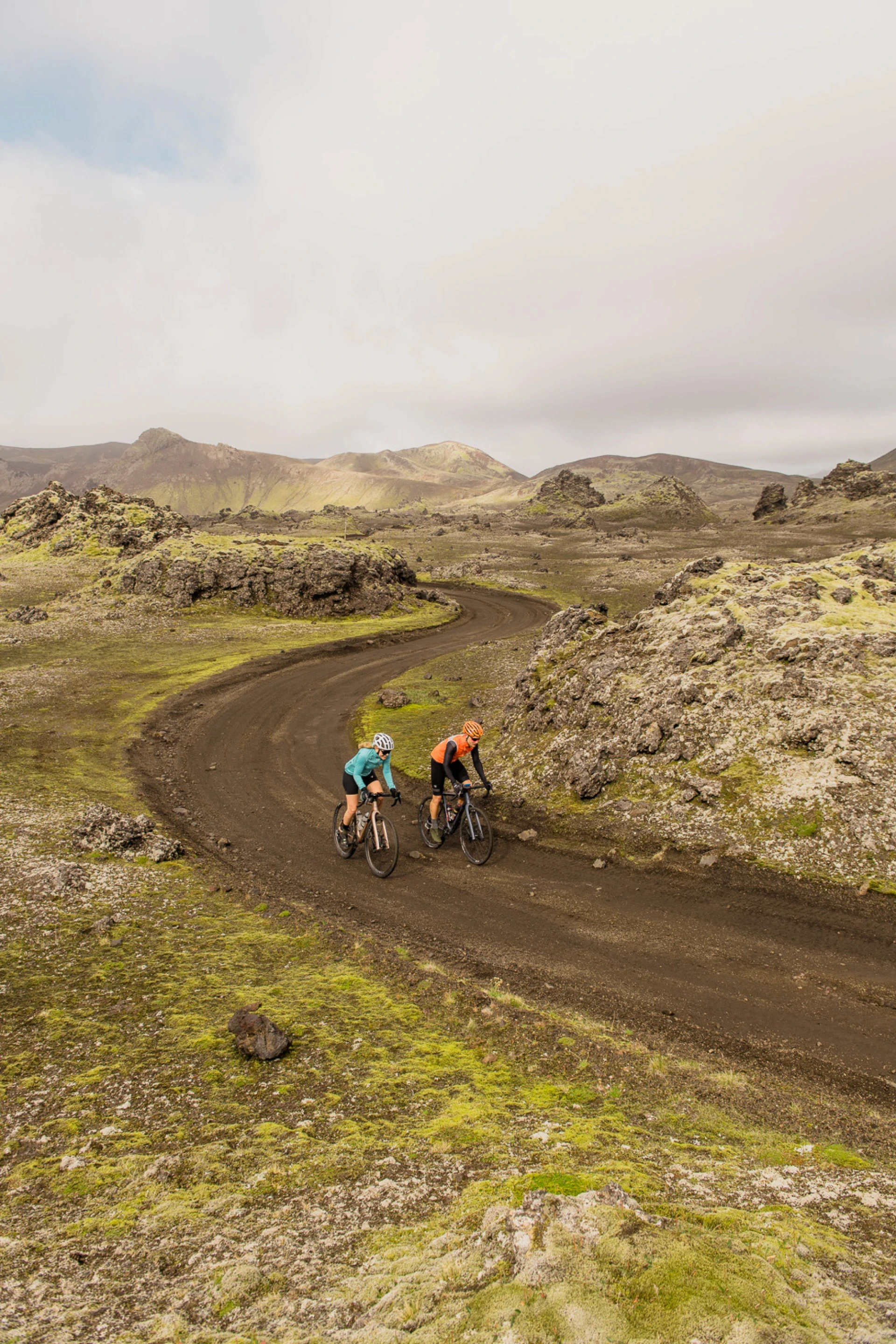Two gravel bike riders pedal through yellow and green moonscapes with lave on hero gravel
