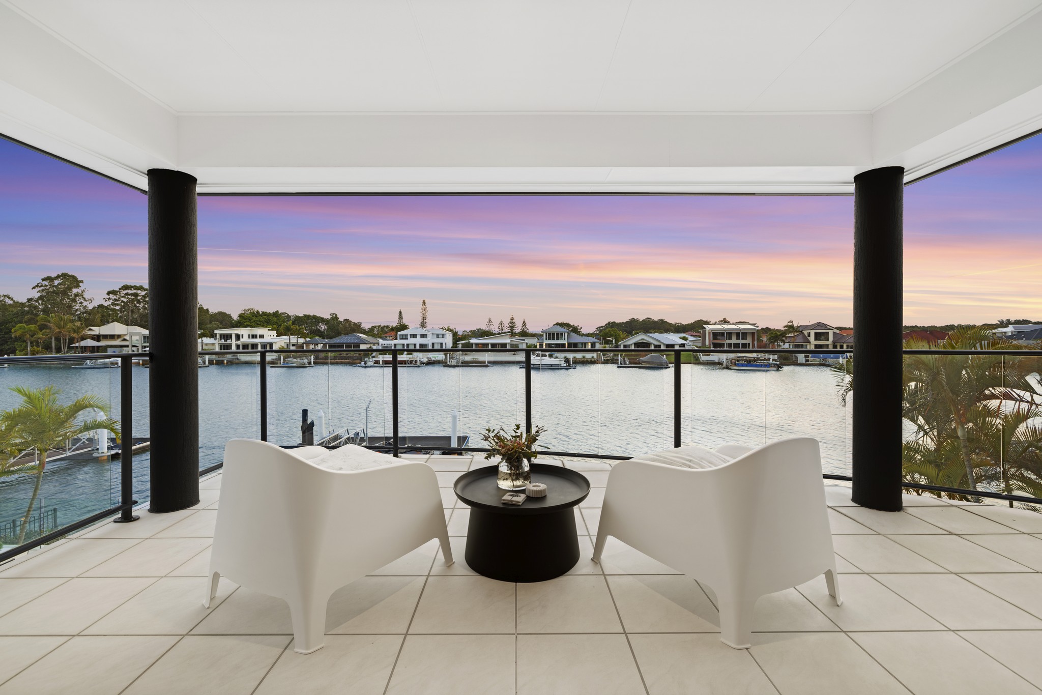 A tranquil view of a luxurious villa with a pool overlooking a serene lake, surrounded by lush greenery.