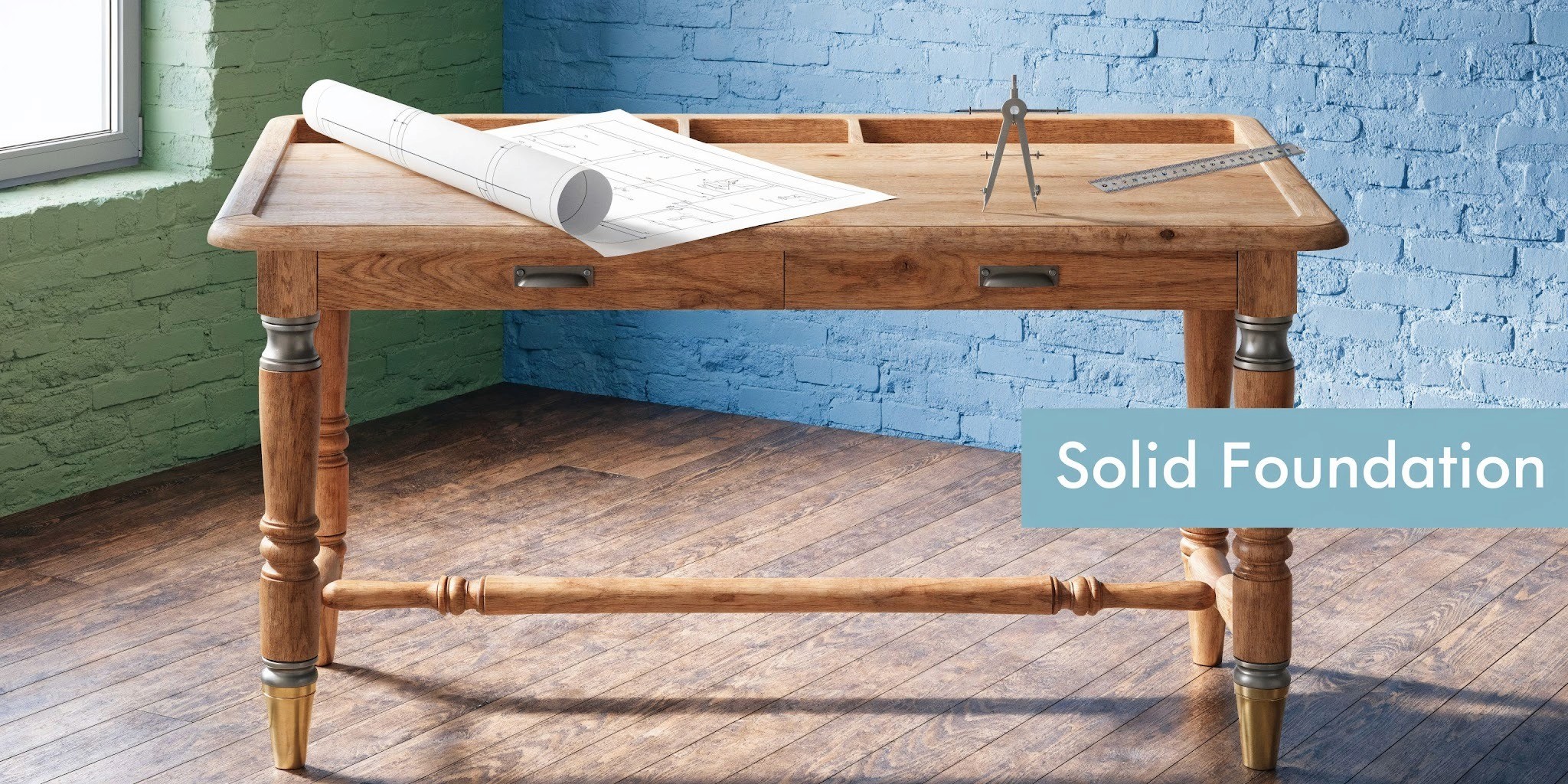A wooden drafting table with architectural blueprints and tools set against a blue and green brick wall.