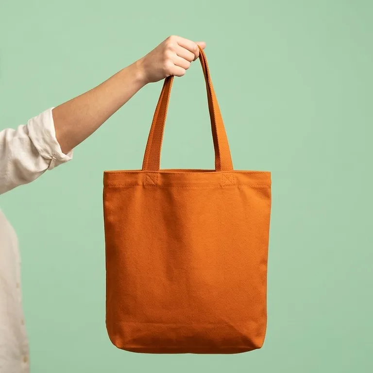 Image of an orange colour tote bag held by its handle by a person on hand 