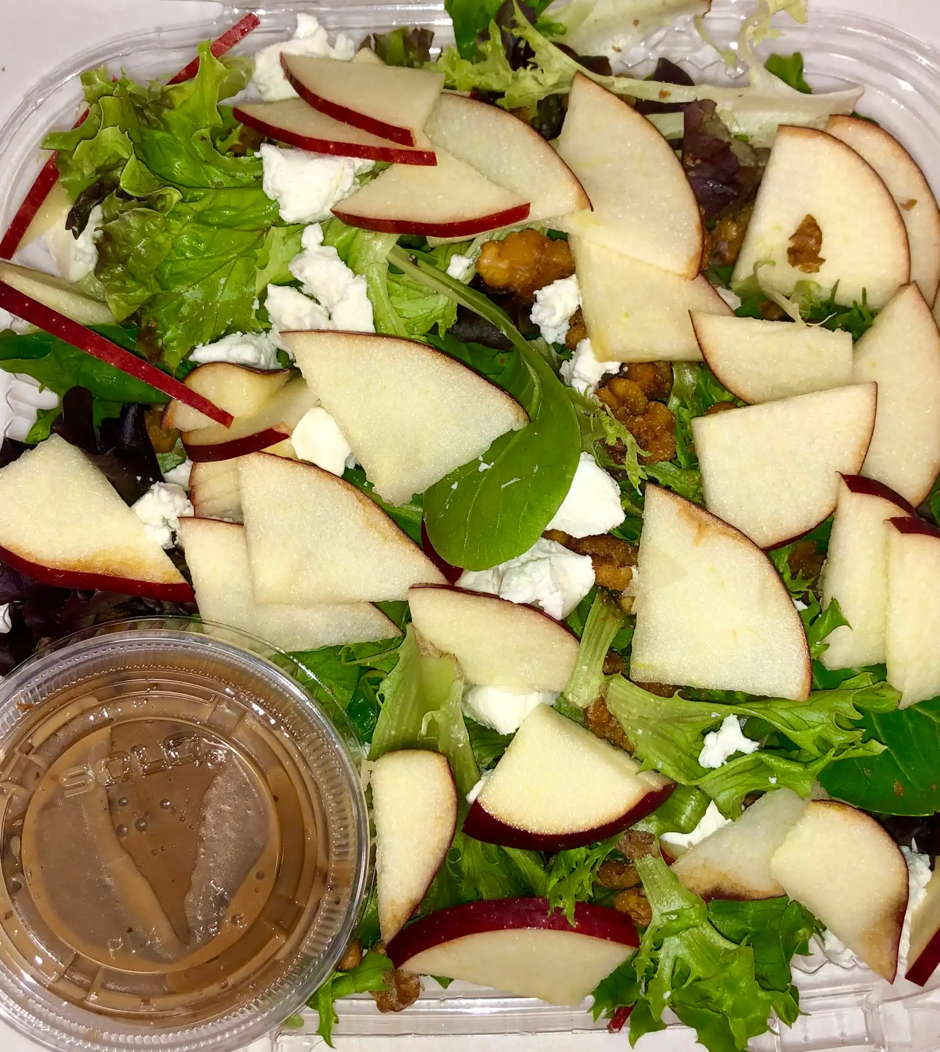 Salad counter with bins of fresh greens, vegetables and toppings