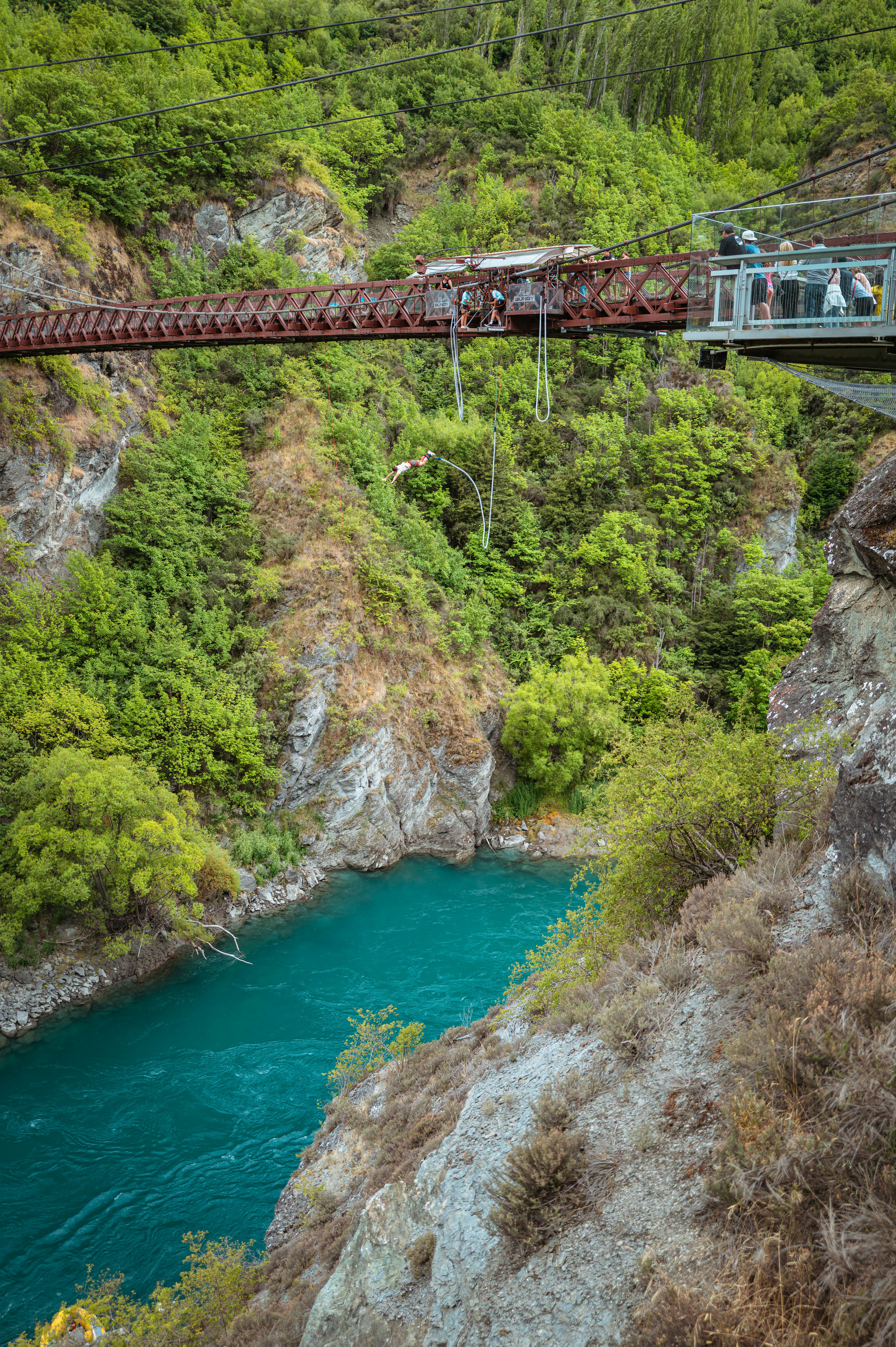 people are walking across a bridge over a river