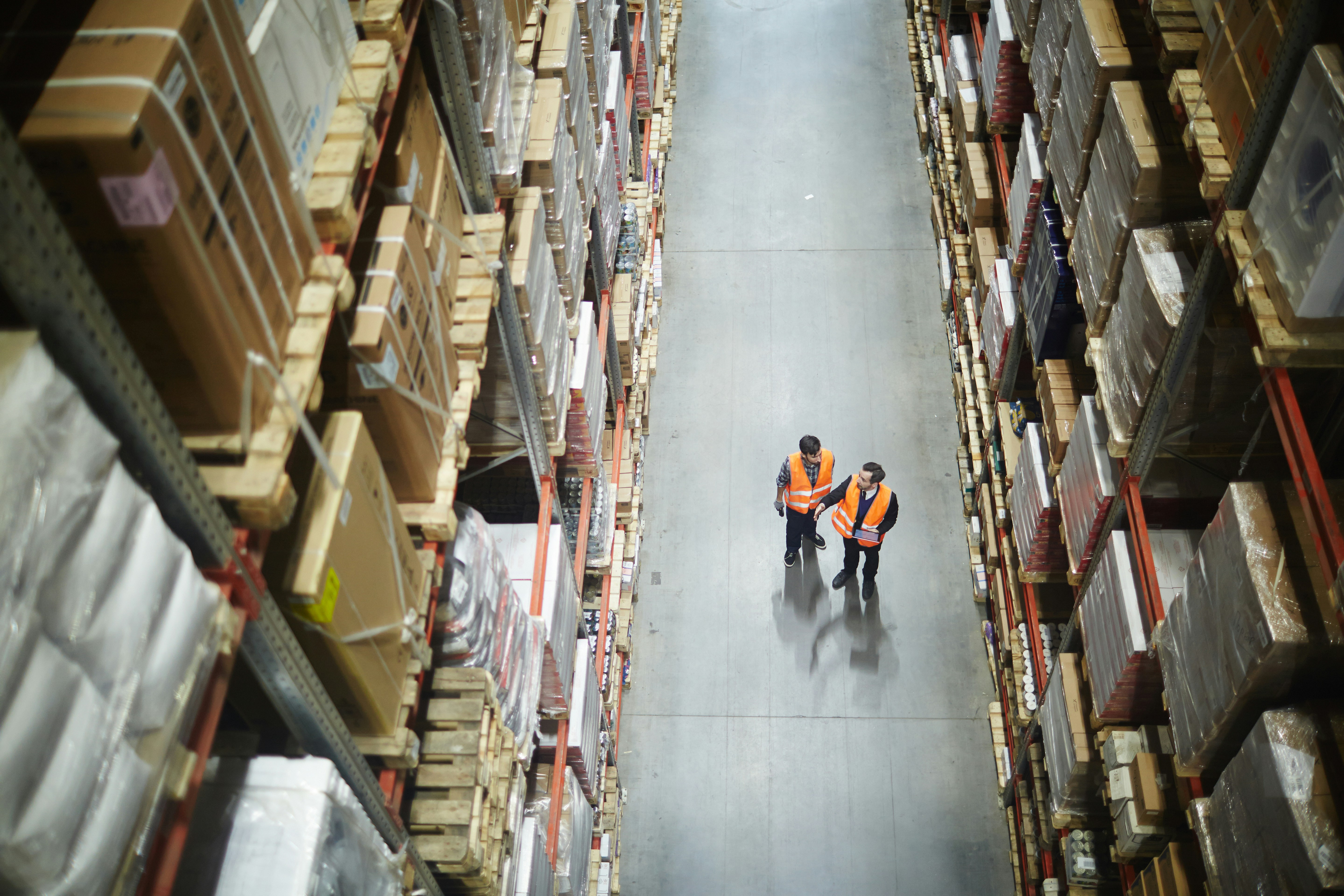 warehouse workers walk down warehouse aisle