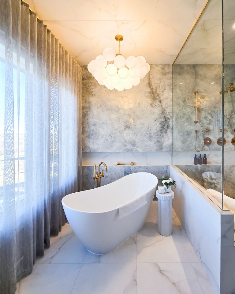 Image of Luxurious primary ensuite bathroom with freestanding tub, marble walls, and KHD Homes design-build renovations.