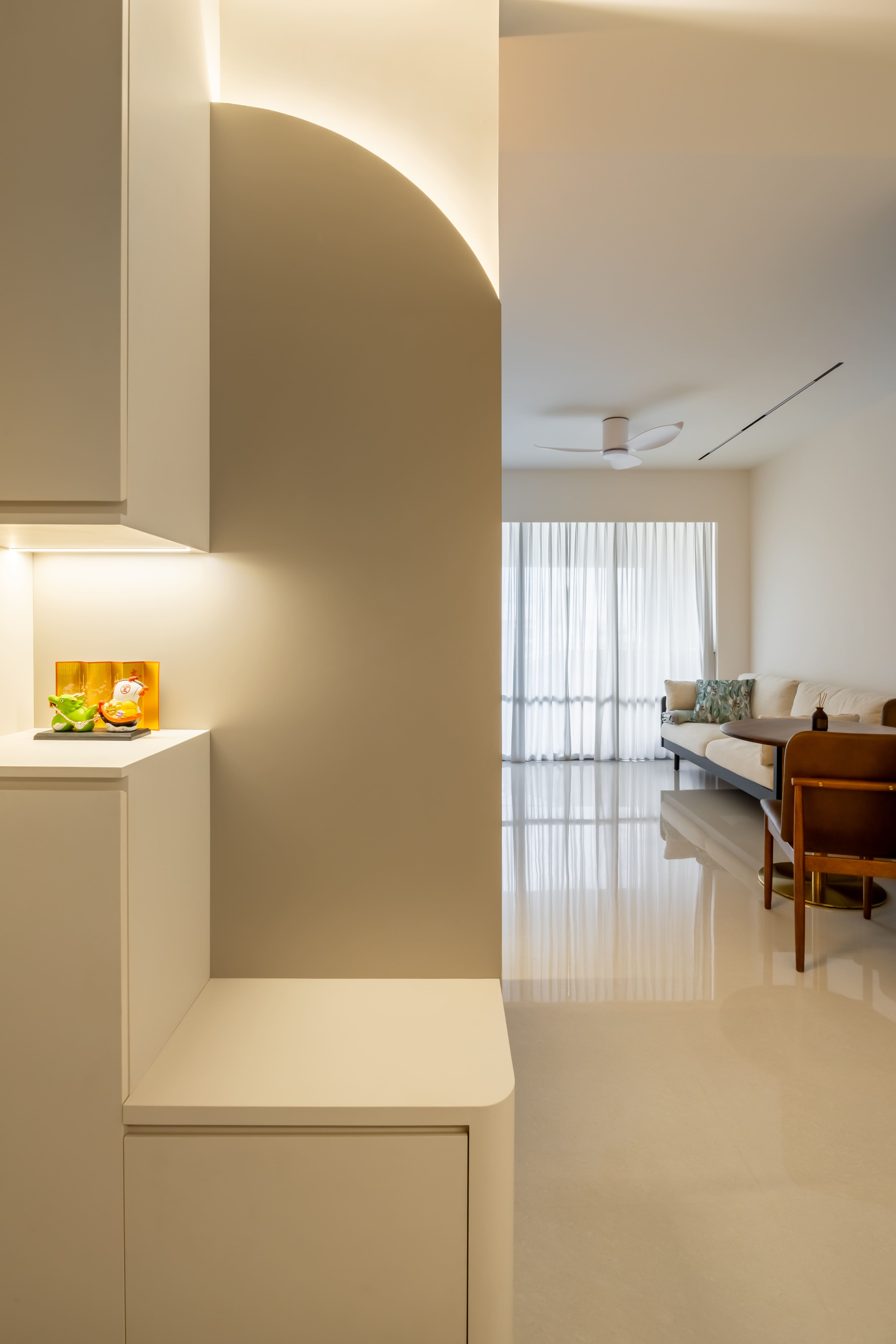 Curved entry niche with hidden LED lighting leading into a sunlit living area.