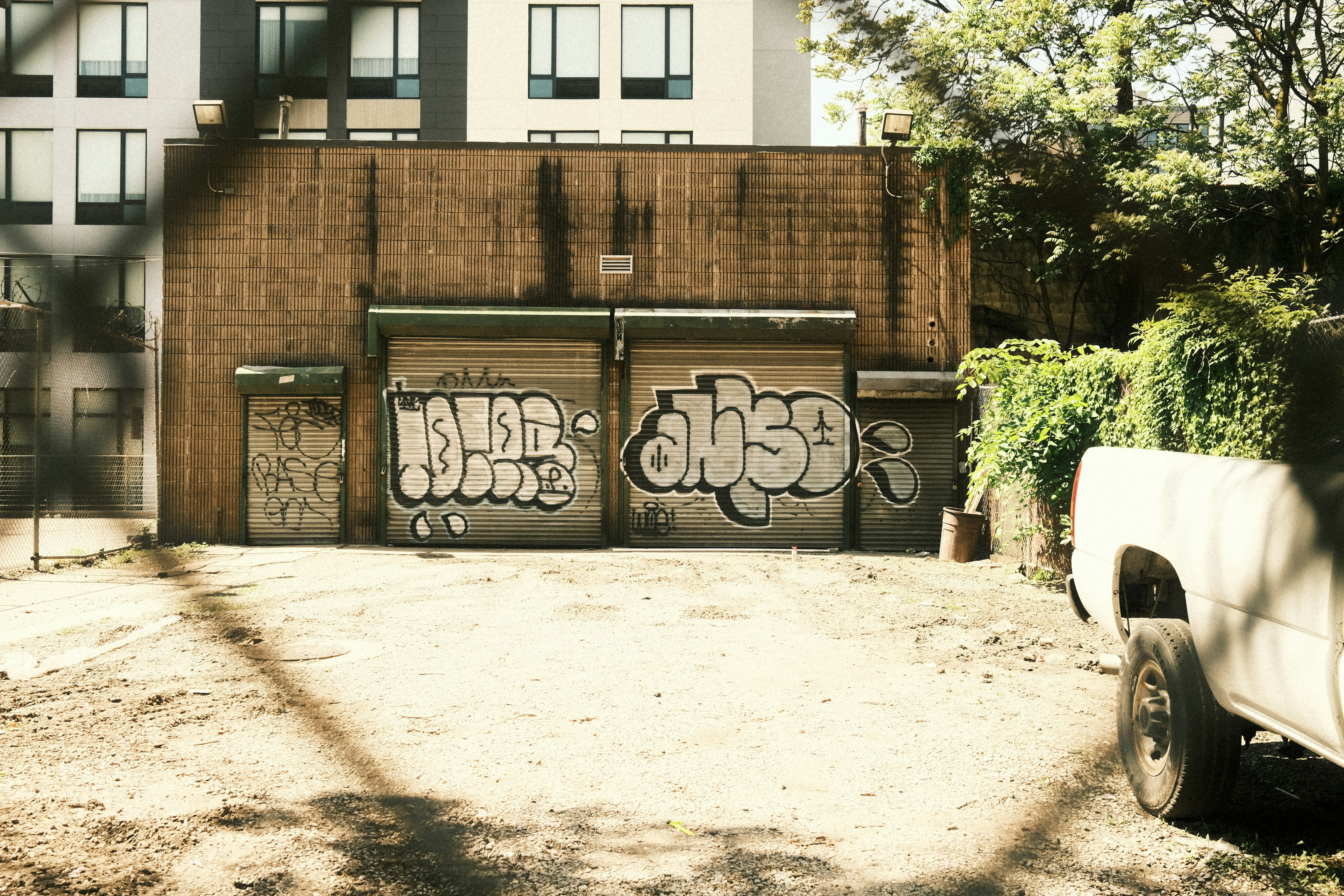 Graffiti covers doors on a weathered brick building.