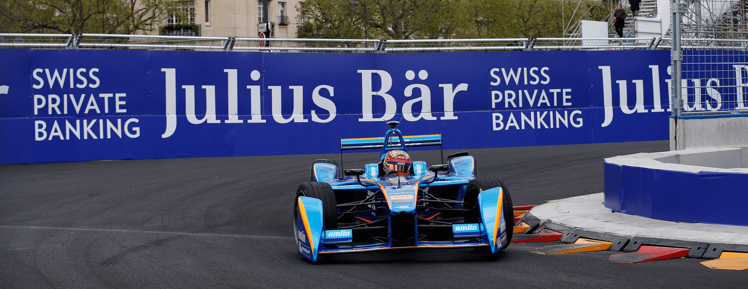 rebranded billboards of Julius Bäralong a race track, and a sponsored car in front