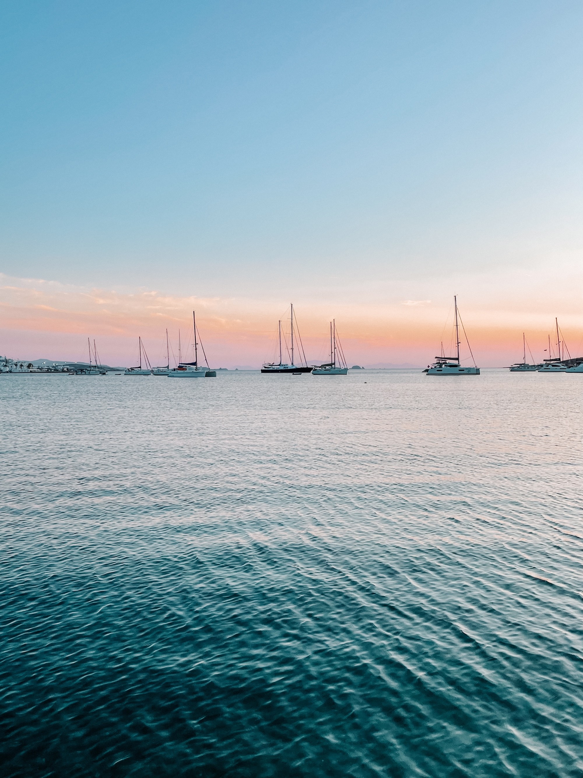 Catamarans in the beautiful Aegean sea, as the sun is setting right into the sea.