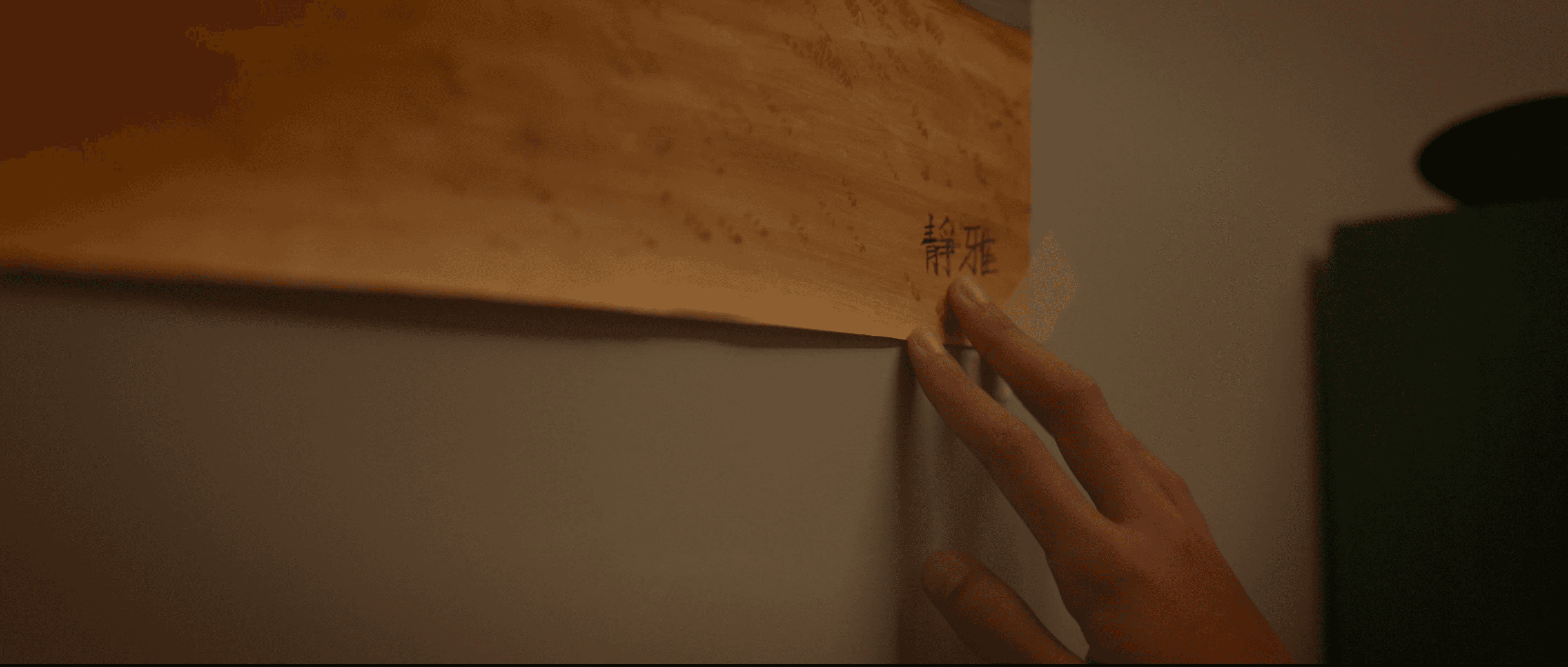 Alice touching a drawing from her childhood which her name is written in the bottom