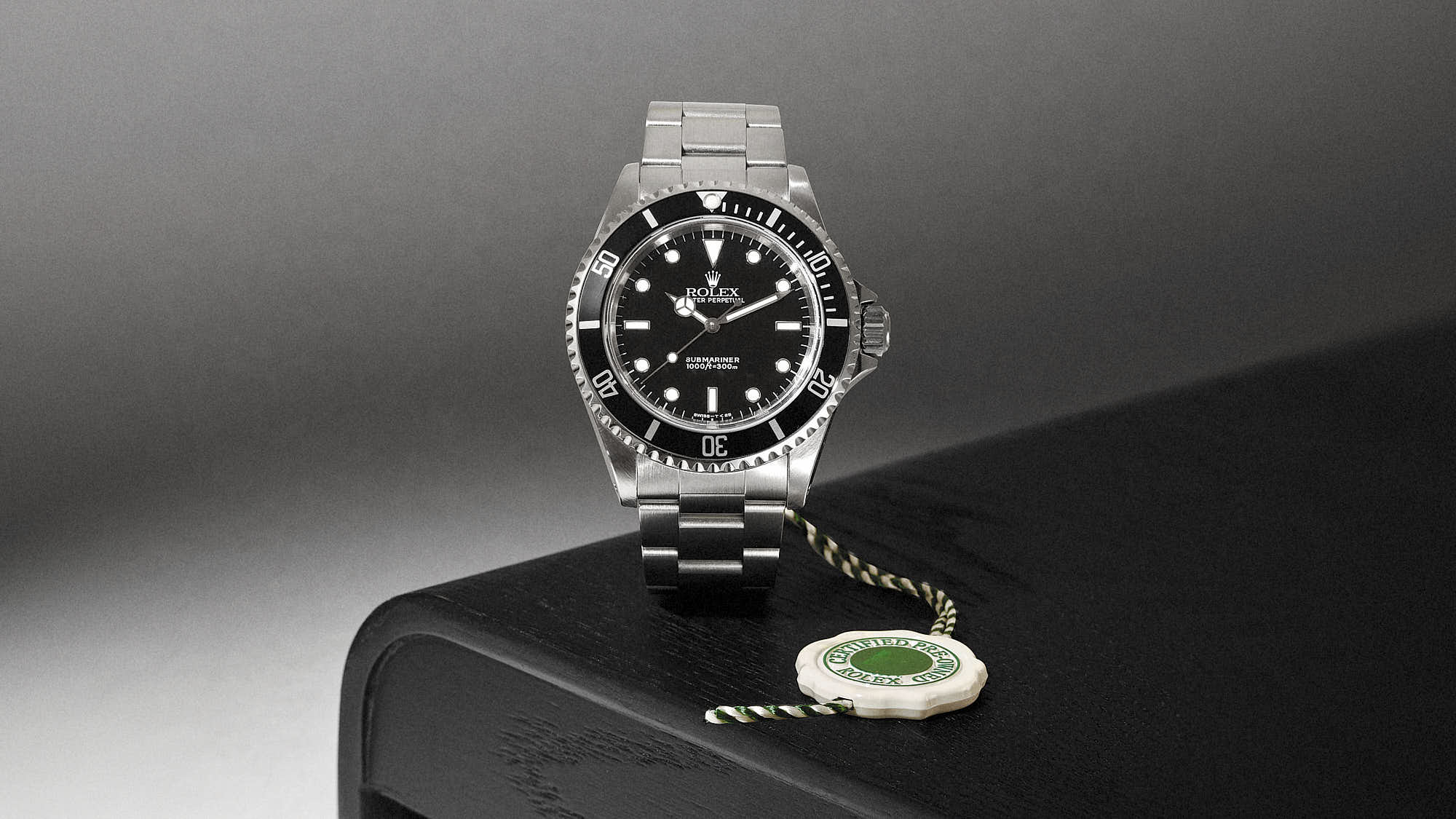 Luxury Rolex Submariner watch with stainless steel bracelet on dark surface.