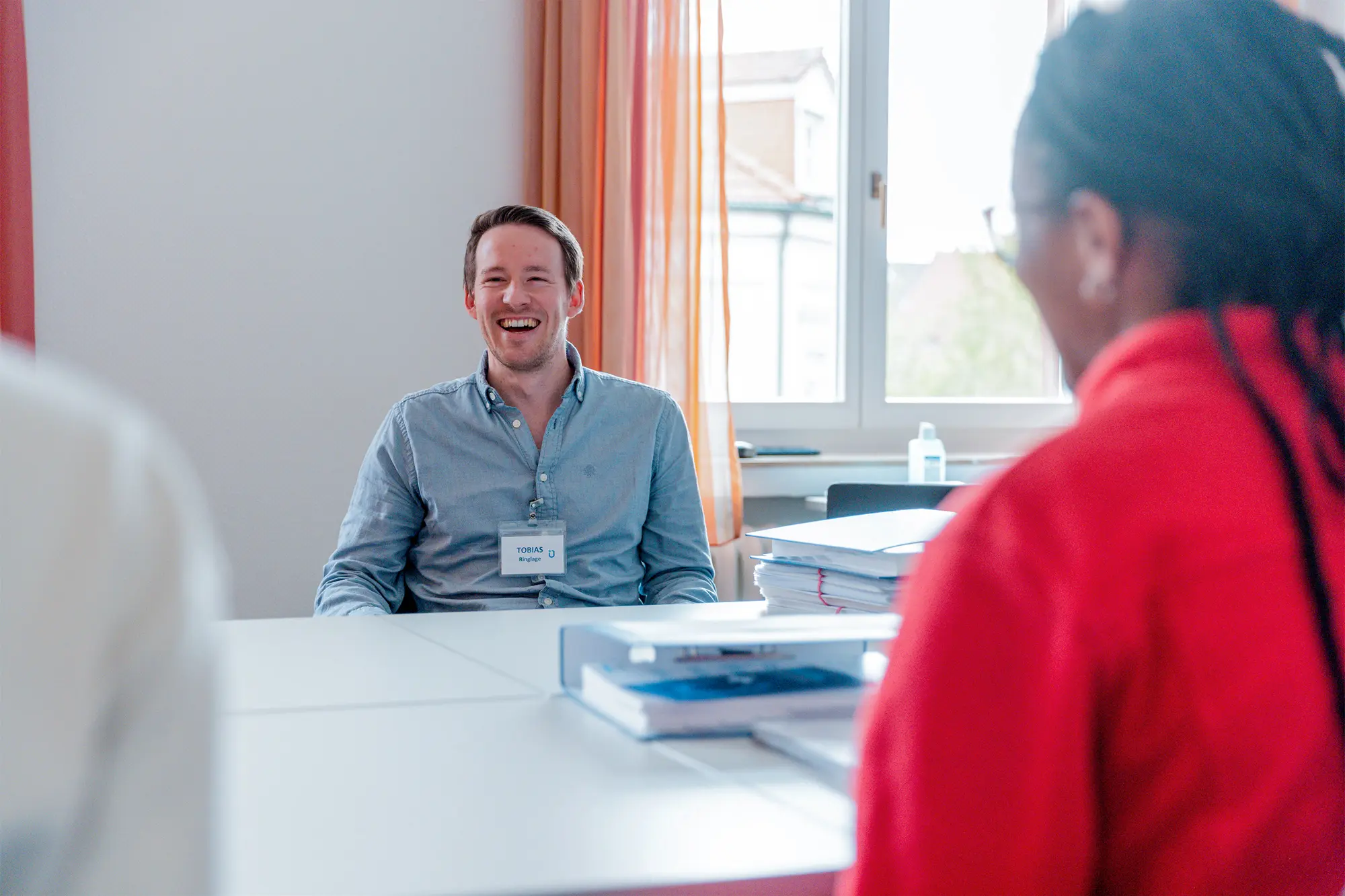 Ein hell beleuchteter Konferenzraum, voll mit Teilnehmenden des SOP Notaufnahme Seminars, die an Tischen sitzen und nach vorne schauen, wo jemand auf einer großen Leinwand was präsentiert.