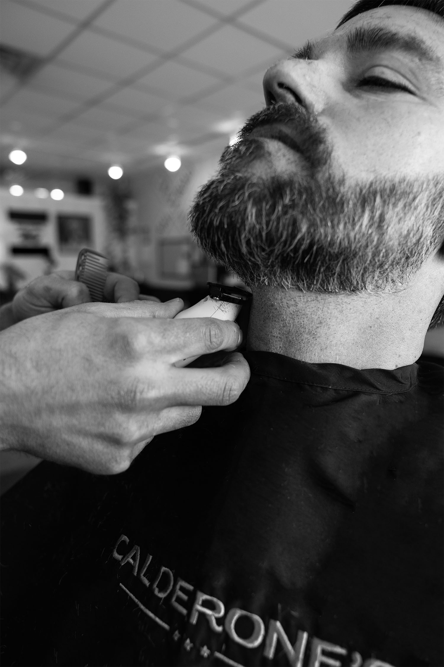 Close-up of a barber trimming a client’s beard during a traditional grooming service at Calderone’s Barbershop