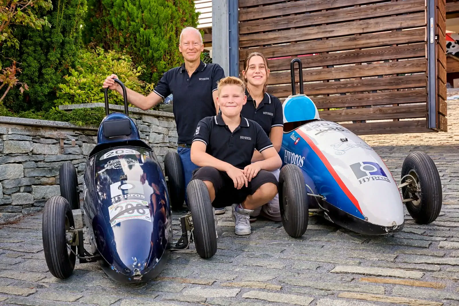 Patrick, Nicolas et Natacha Binczak posant avec leurs deux caisses à savon Hypros