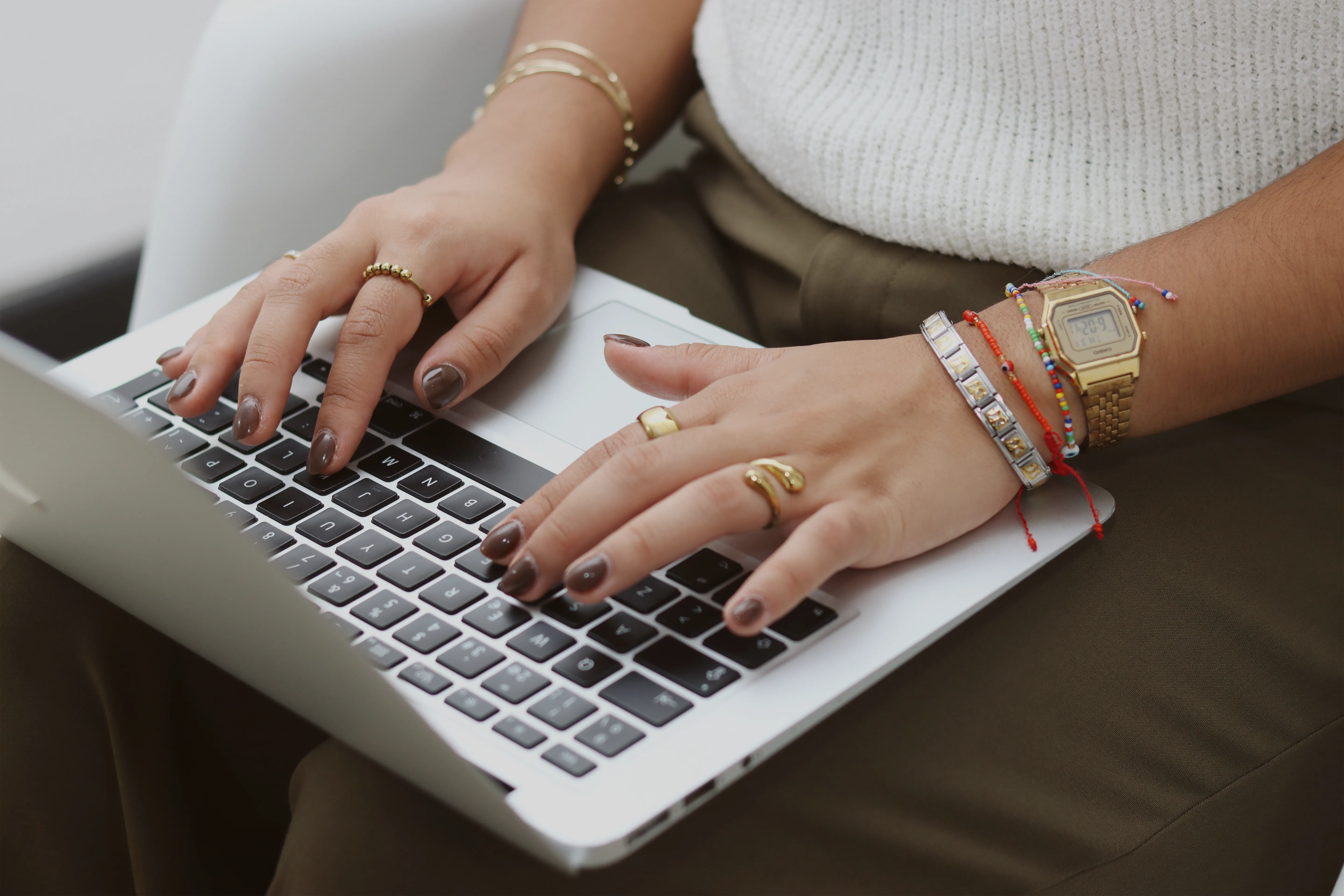 Manos femeninas escribiendo en laptop plateada.