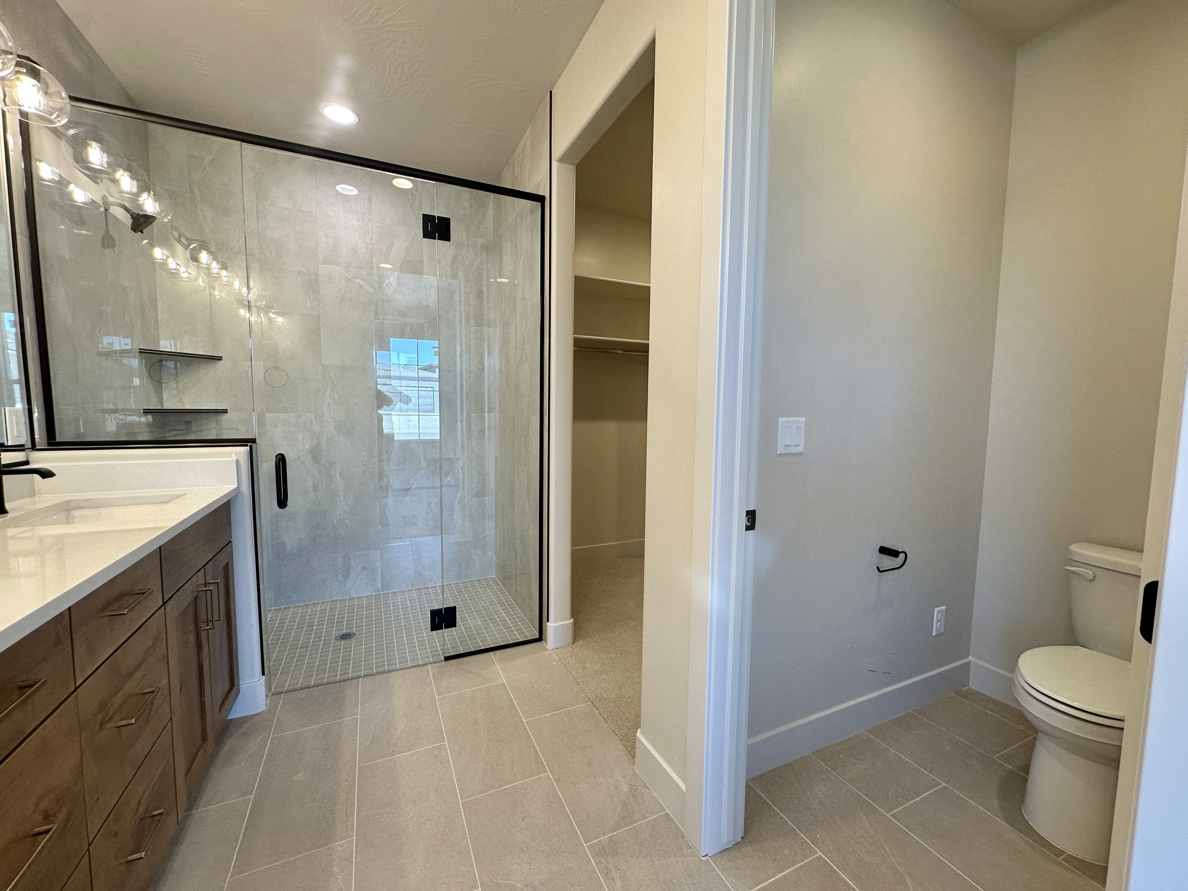 Master bathroom at The View at Falcon Ridge in Hurricane, Utah, highlighting walk-in shower, dual vanities, and light-filled, luxurious design.